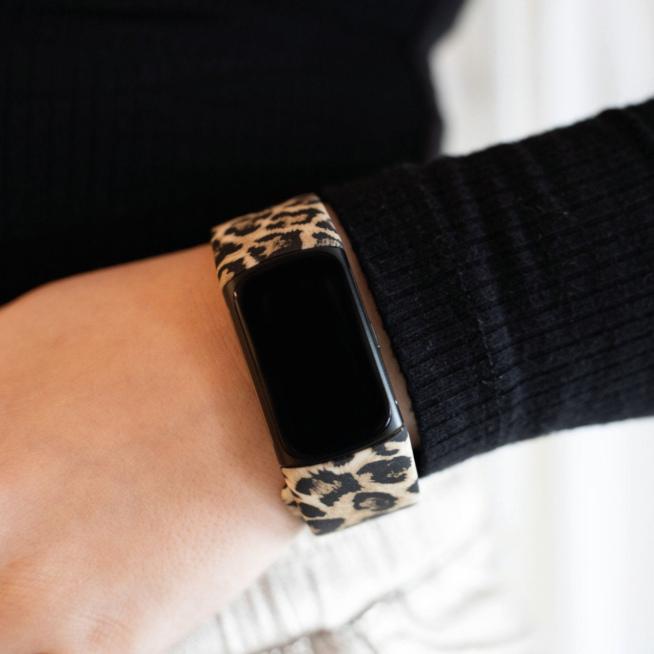 Handgelenk mit Smartwatch und Leopardenmuster-Armband.