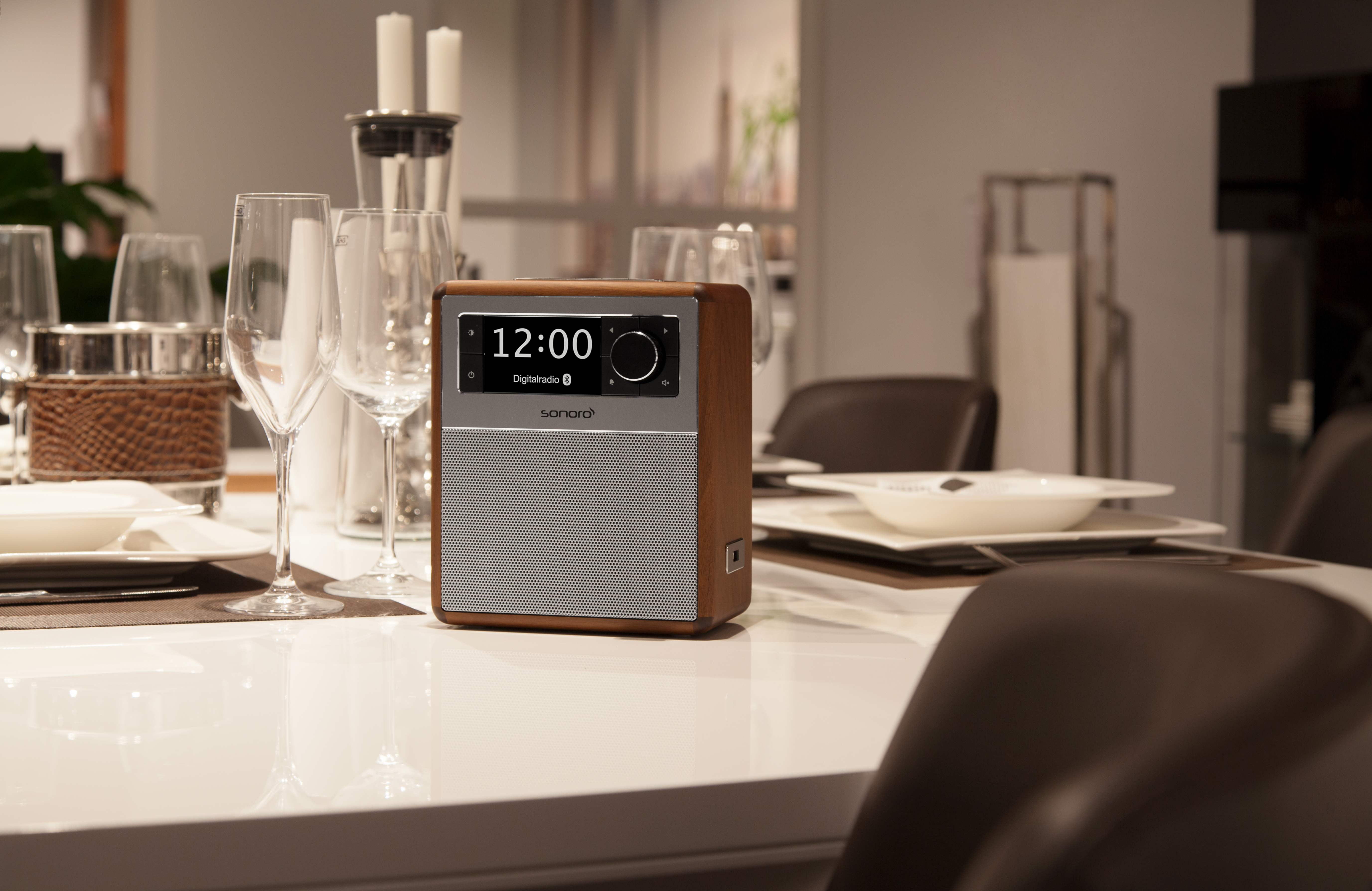 Ein Radio auf einem Tisch, der für das Abendessen gedeckt ist. Gläser, Teller und Kerzen sind sichtbar.