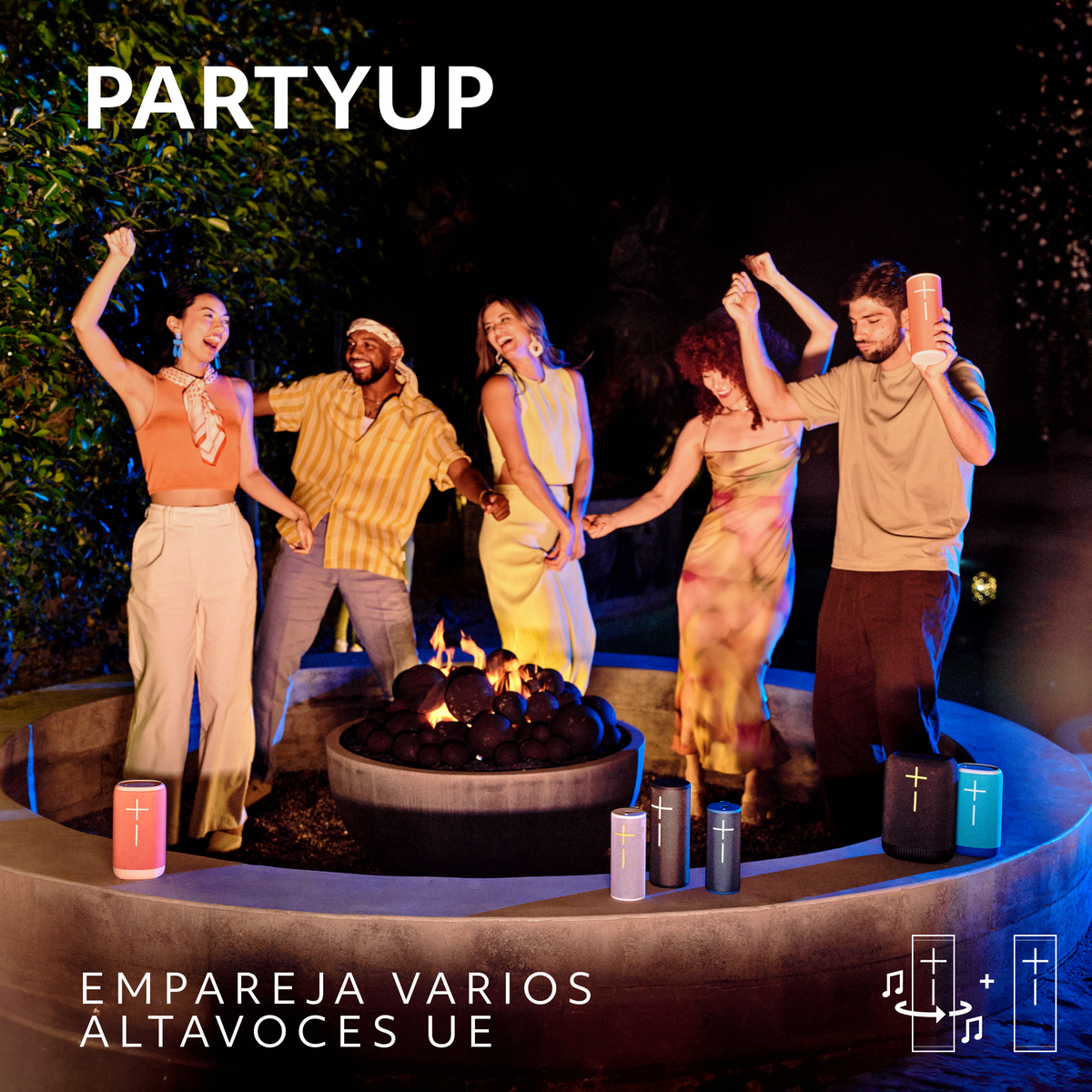 Ludzie tańczą wokół paleniska w nocy z kolorowymi głośnikami. Tekst: PARTYUP, EMPAREJA VARIOS ALTAVOCES UE.