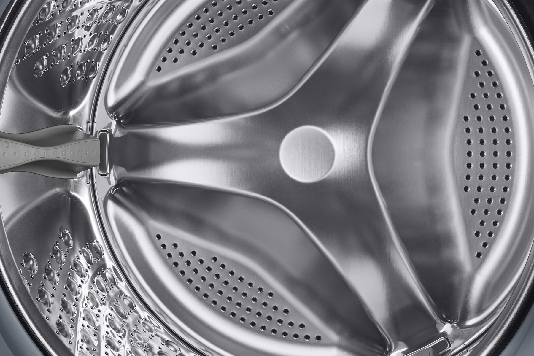 Zbliżenie bębna pralki, pokazujące jego wnętrze z metalowymi powierzchniami.