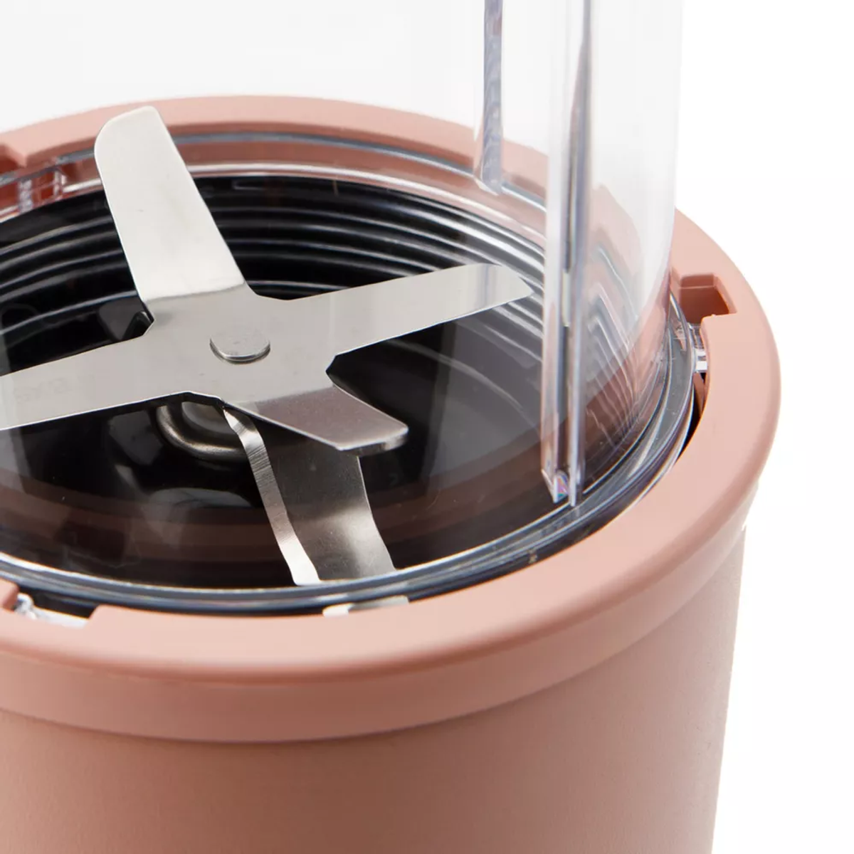 Zbliżenie ostrza i pojemnika blendera. Pojemnik jest różowo-brązowy.