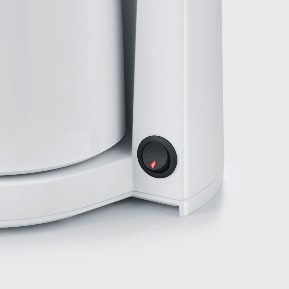 Primo piano di un elettrodomestico bianco con interruttore nero illuminato. Luce rossa accesa.