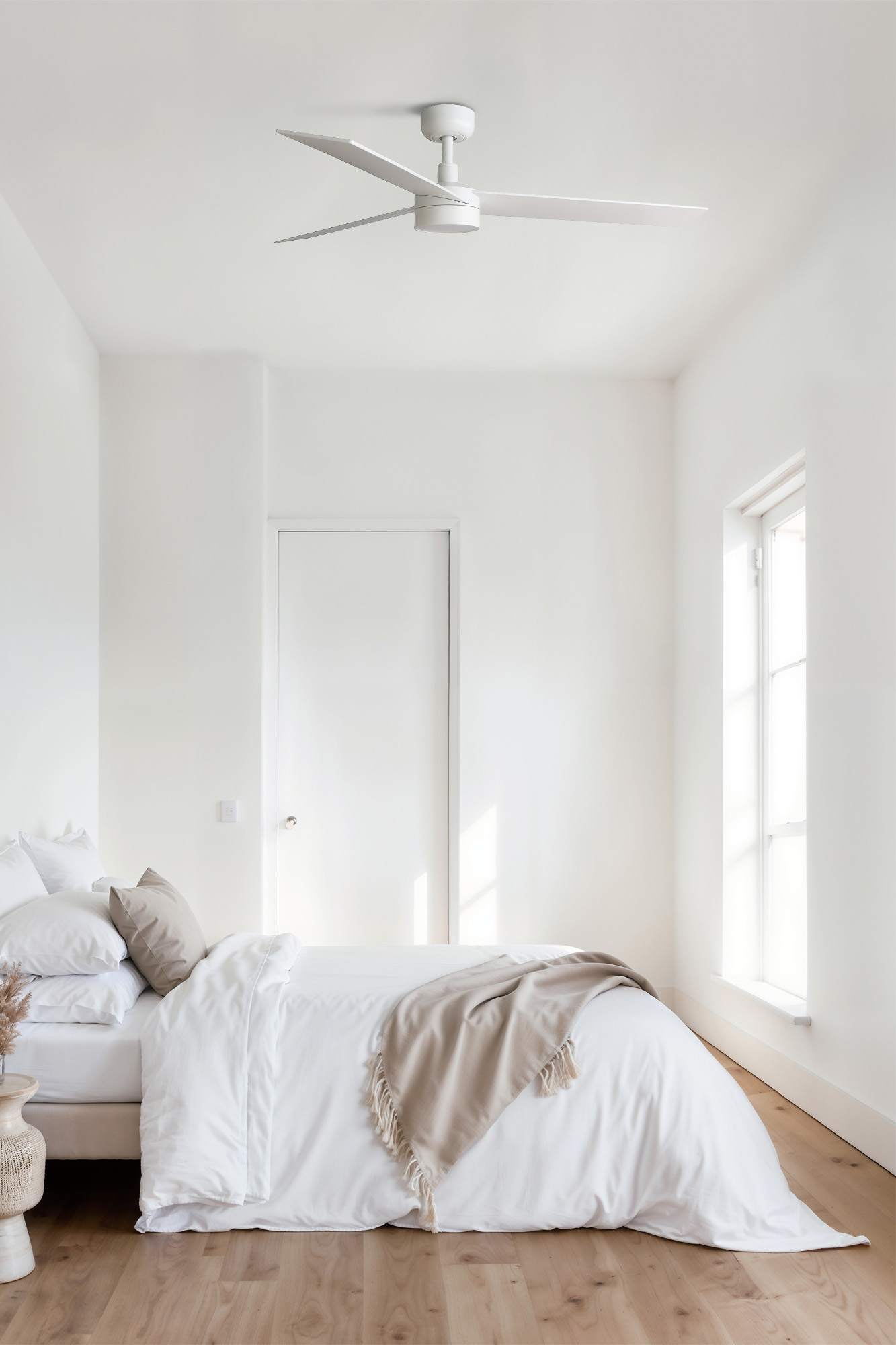 Ein Schlafzimmer mit weißem Bett, weißen Wänden und einem weißen Deckenventilator.