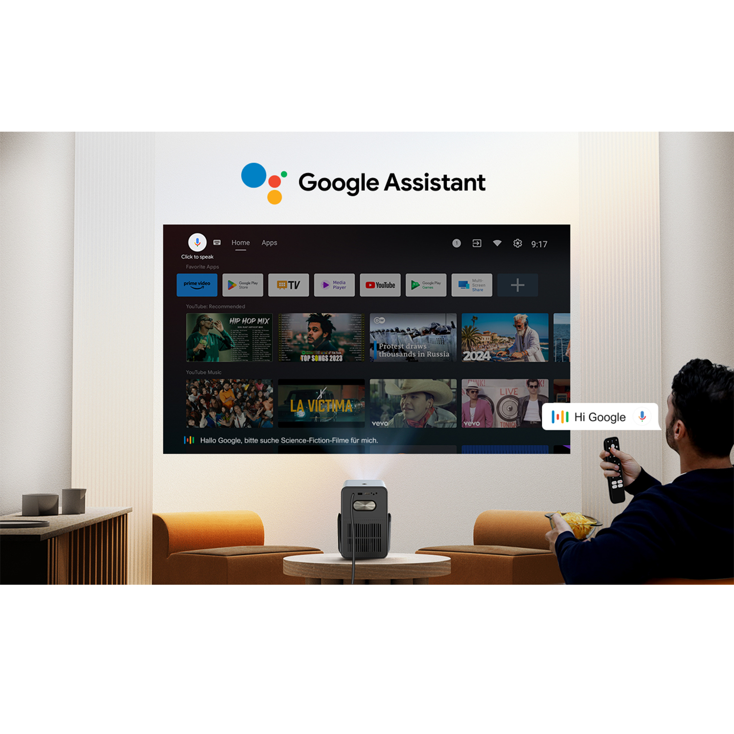 Eine Person nutzt Google Assistant auf einem Projektor. Ein großer Bildschirm zeigt eine Smart-TV-Oberfläche.