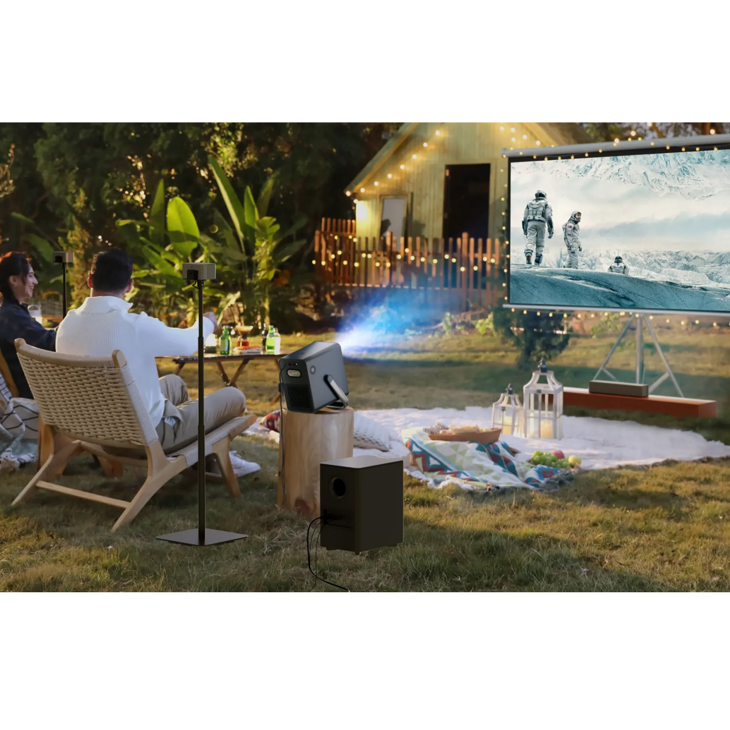 Konfiguracja kina plenerowego: projektor, ekran, ludzie oglądający i oświetlenie otoczenia.