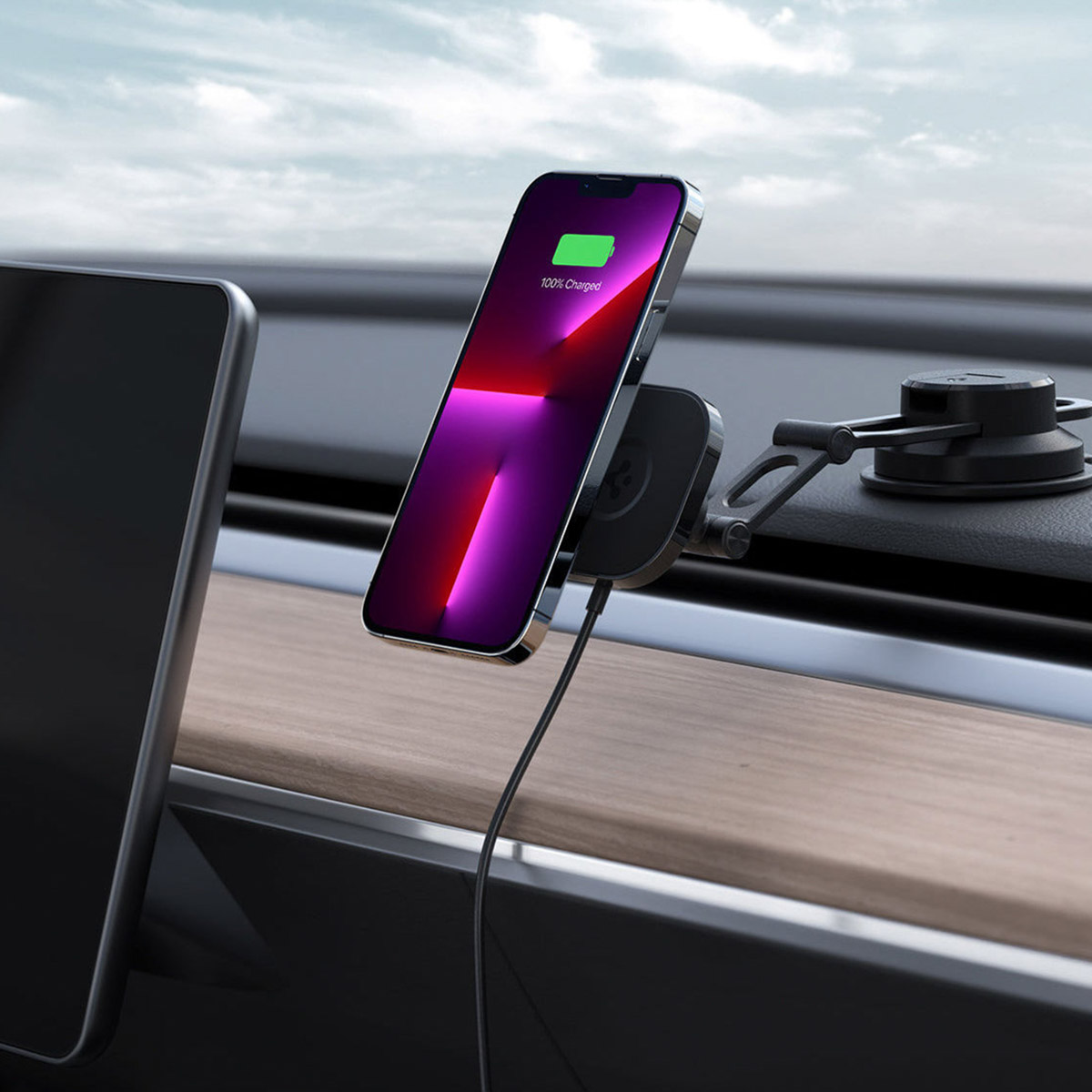 Telefoon die oplaadt in een autohouder. De telefoon is zwart en is 100% opgeladen.