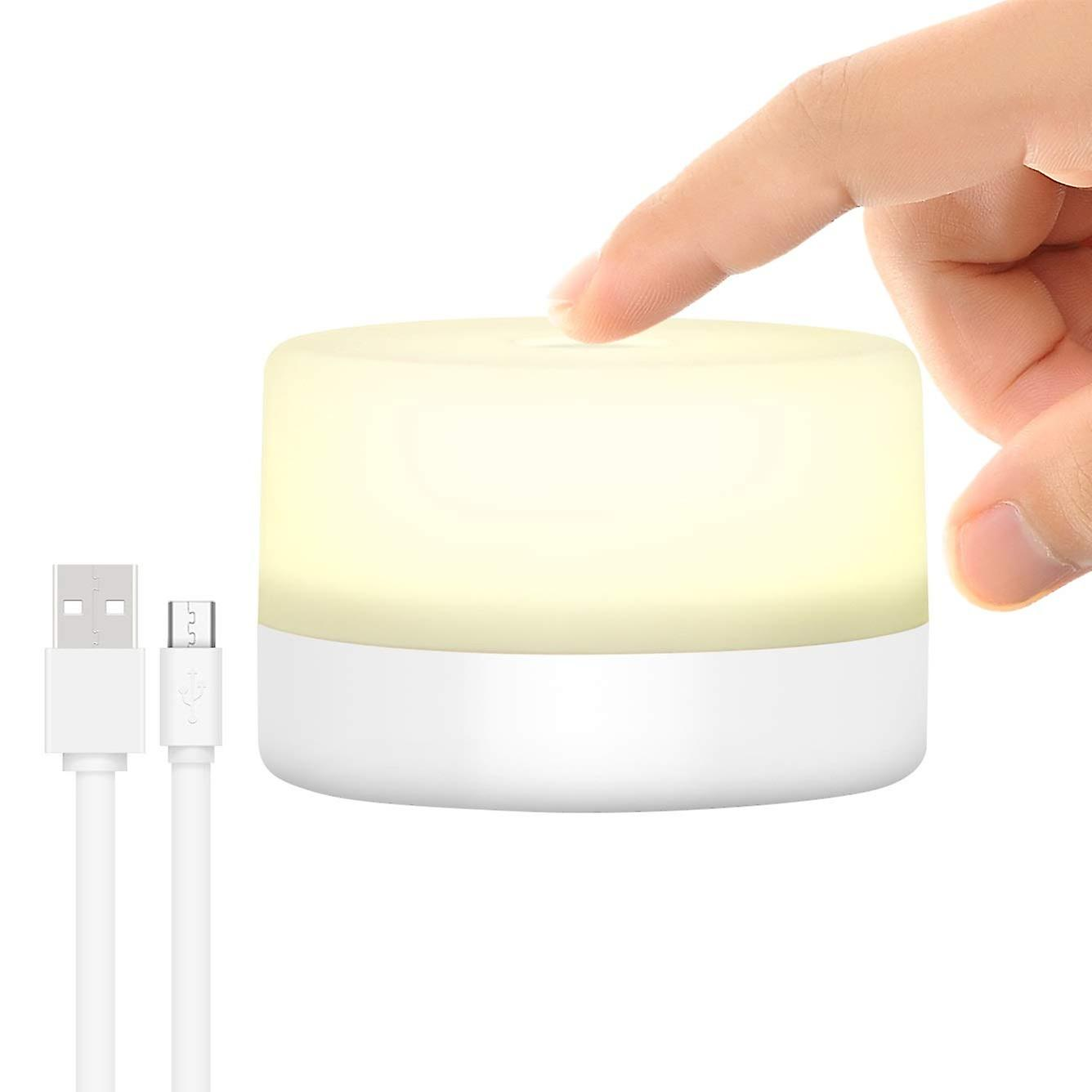Eine Hand drückt auf einen leuchtenden Zylinder. USB- und Micro-USB-Kabel befinden sich links.