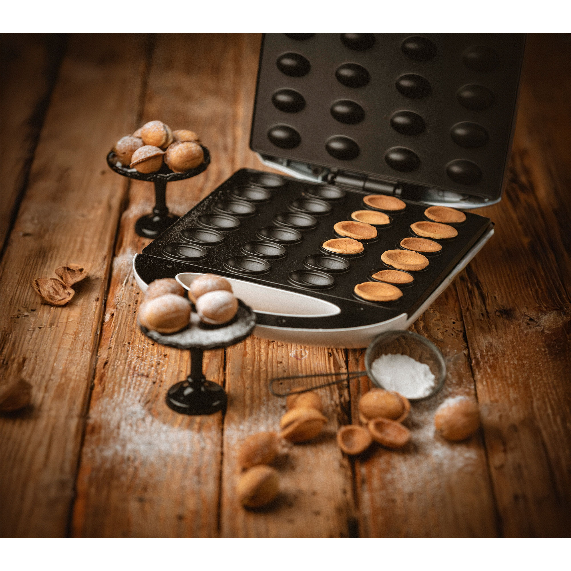 Aparato con productos horneados, pastelitos en soportes, harina, nueces, mesa de madera.