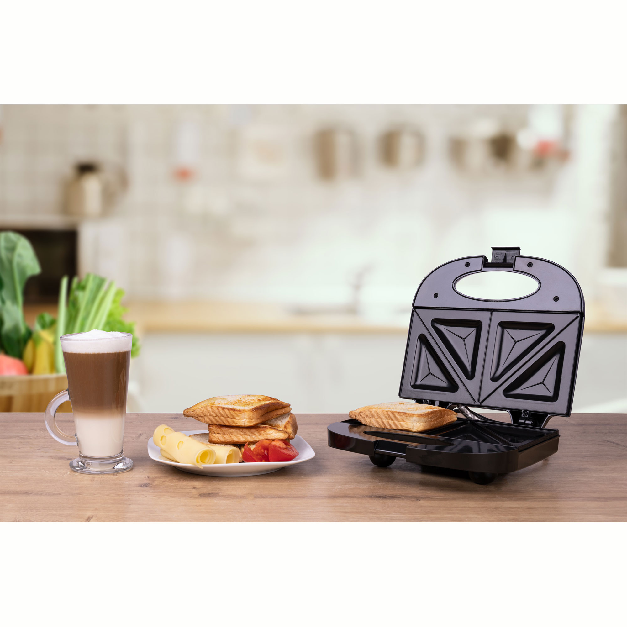 Una tostadora de sándwiches con un sándwich dentro. Al lado un café con leche y otros alimentos.