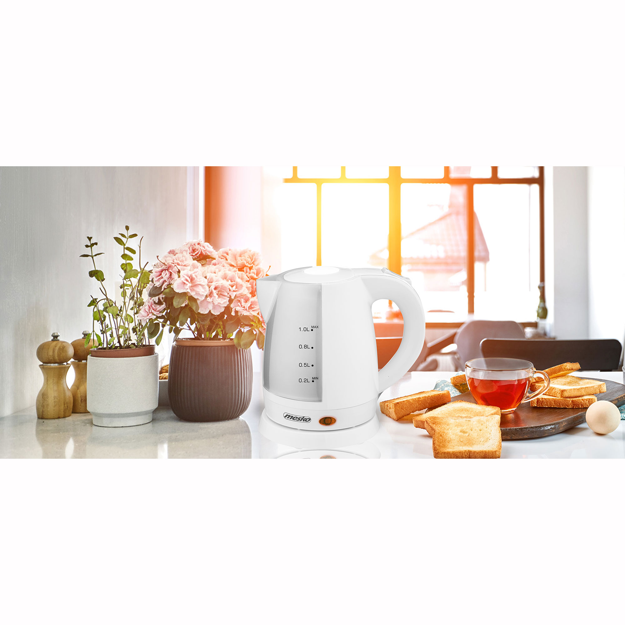 Hervidor eléctrico blanco sobre una mesa con tostadas, una taza de té y flores, en interiores.