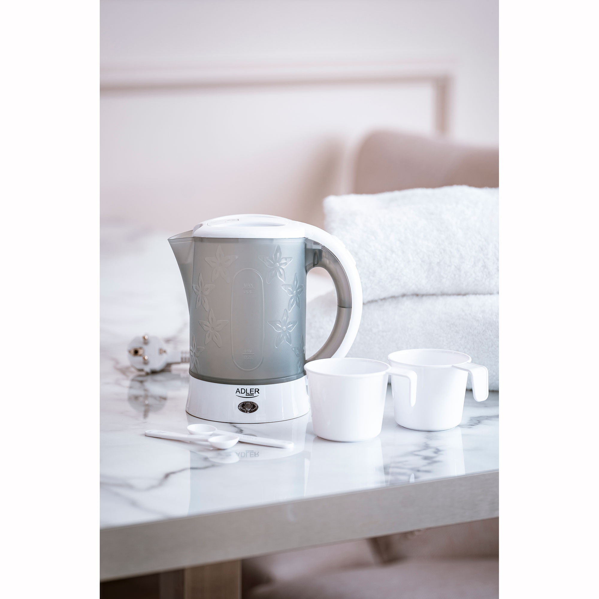 Biały czajnik elektryczny z dwoma filiżankami i białym tłem.