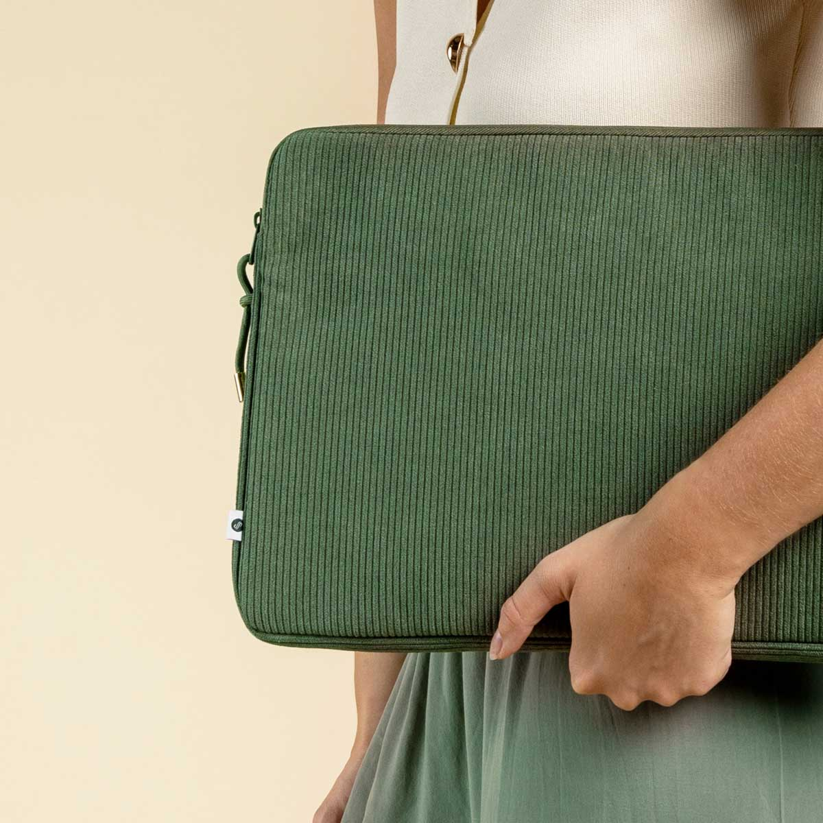 Green corduroy laptop sleeve. A person is holding it.