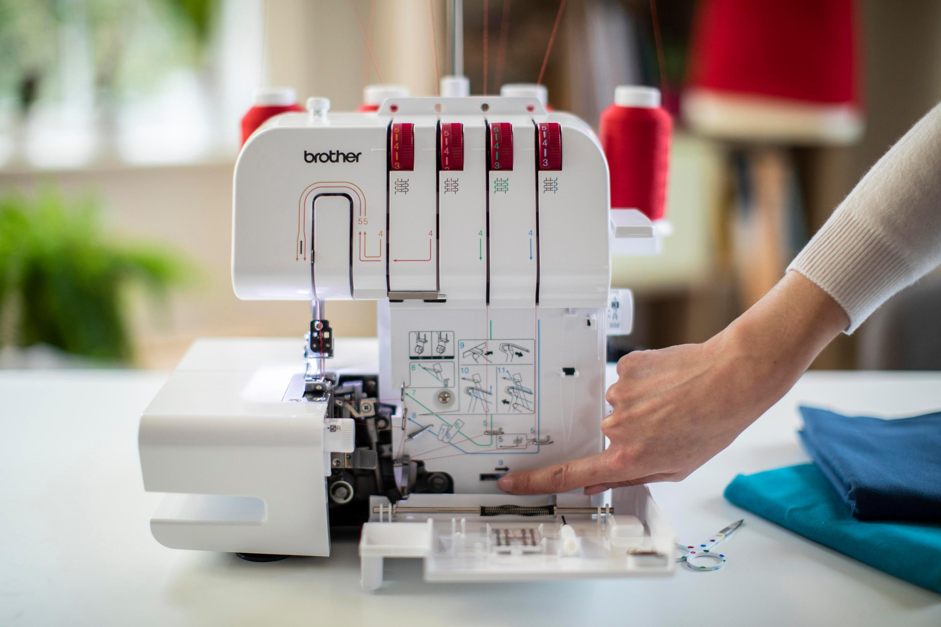 Biała owerlok Brother z czerwonymi szpulkami nici i ręką regulującą ustawienia.