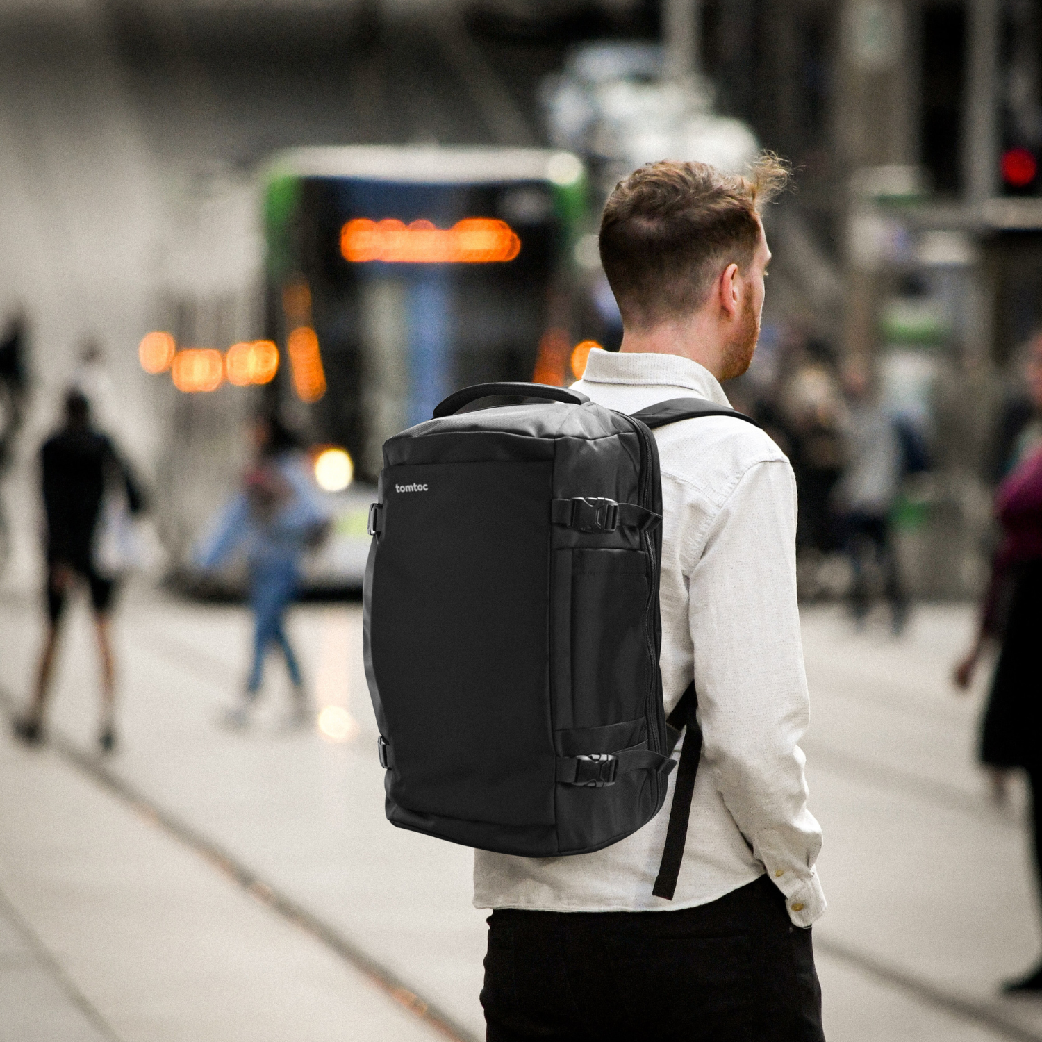 Man with black backpack standing on the street. 