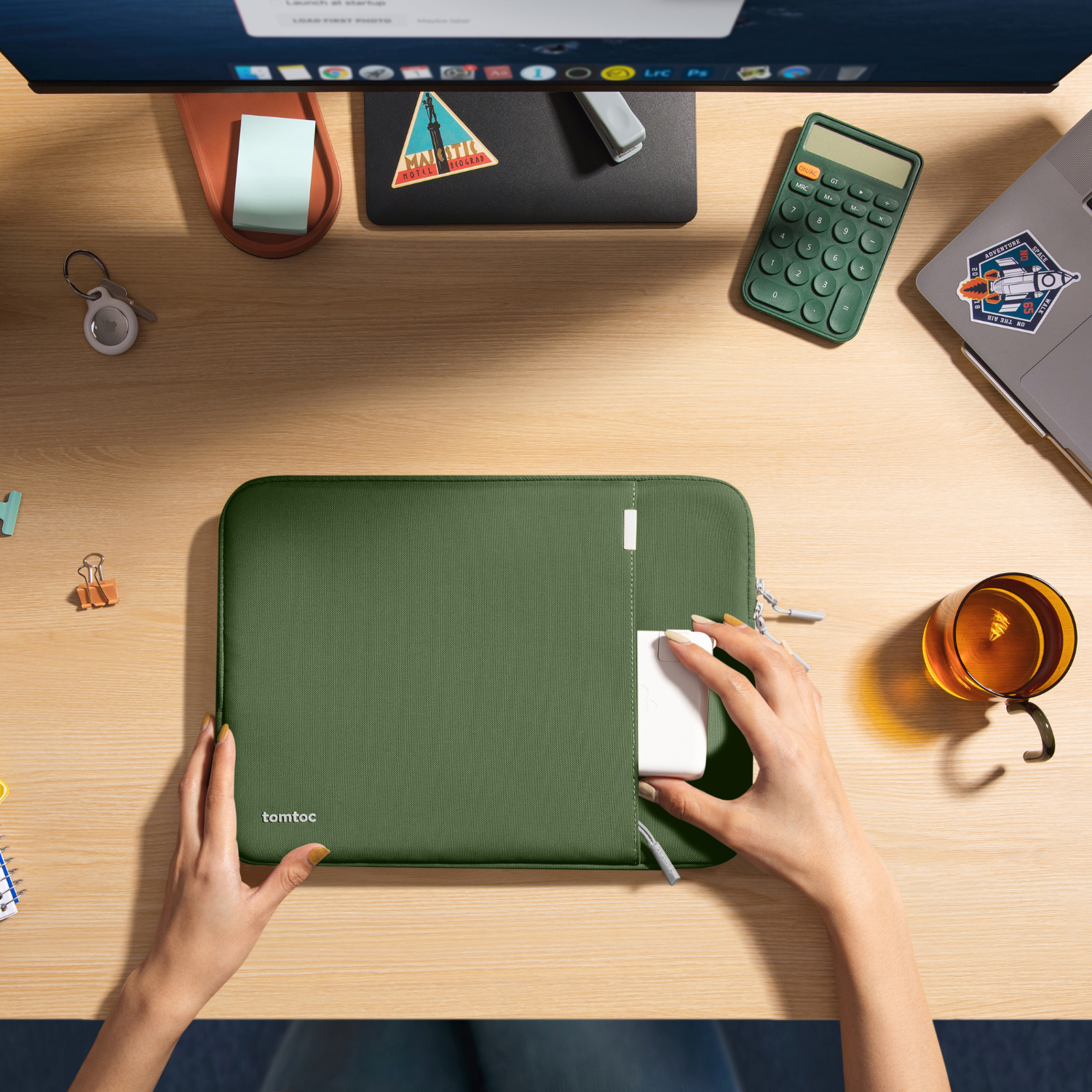 Widok z góry na zieloną torbę na laptopa na biurku z akcesoriami i laptopem.