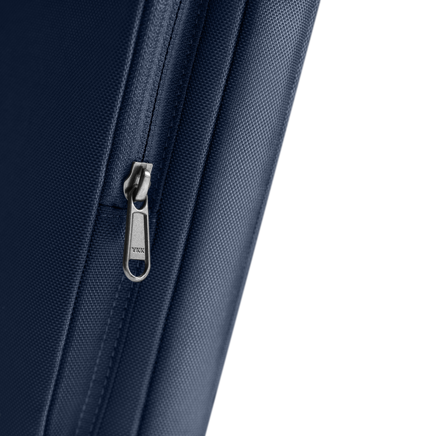 Primo piano di una cerniera di una borsa blu navy con tirante argentato. La cerniera è marchiata YKK. Sfondo bianco.