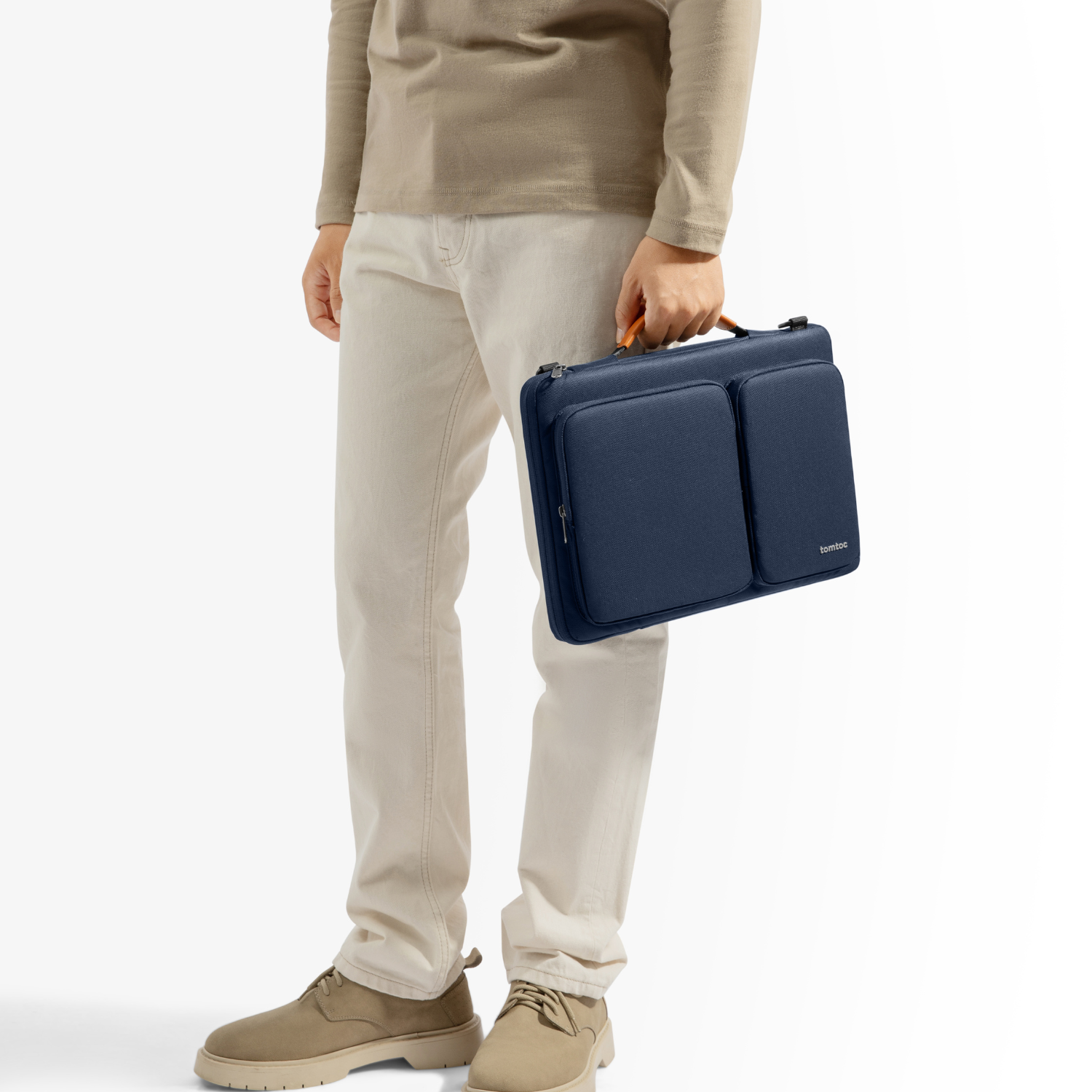 Uomo che tiene in mano una custodia blu per laptop con manico. Indossa una camicia e pantaloni beige. Bianco.