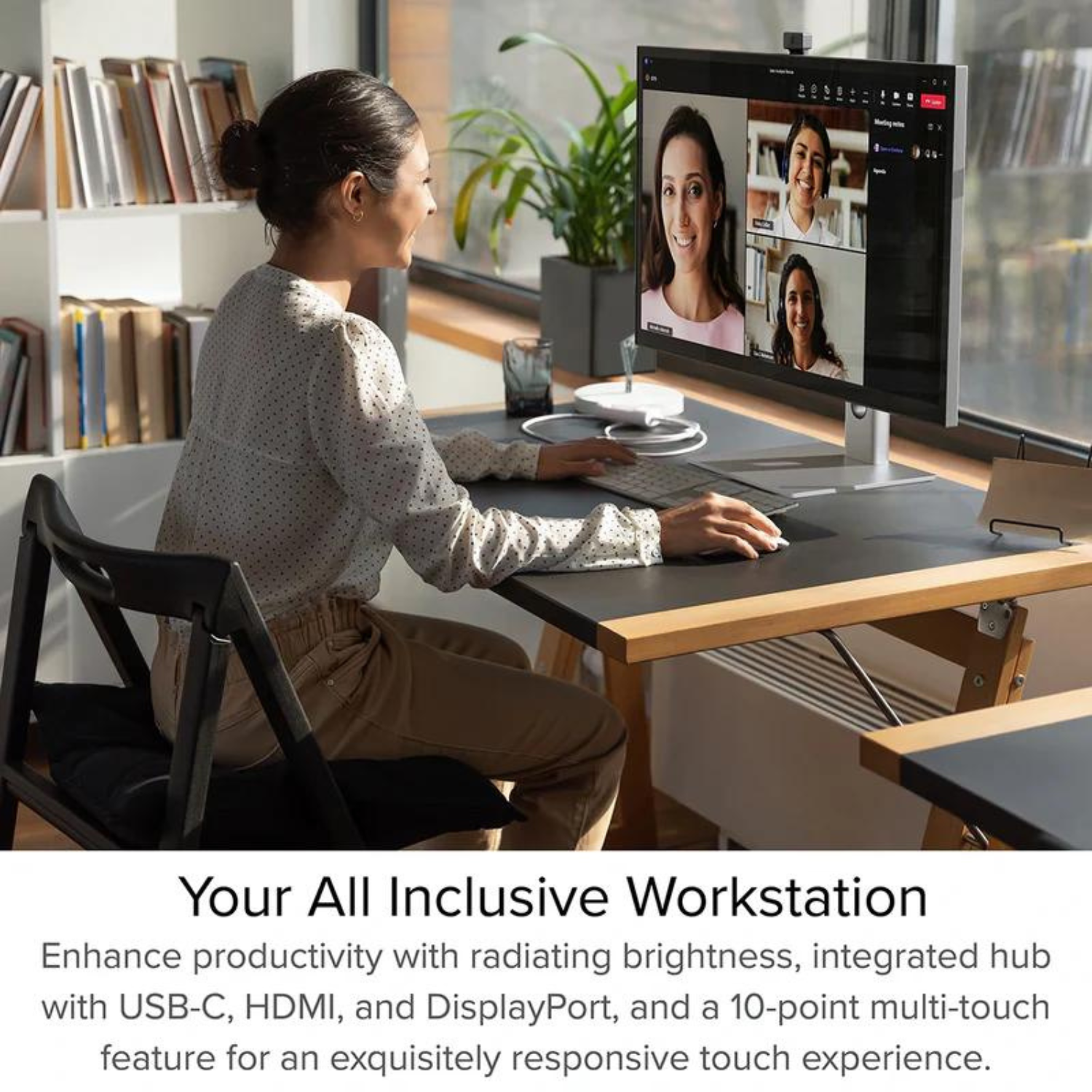 Kobieta pracująca przy biurku z monitorem. Na monitorze widać połączenie wideo. Ma na sobie białą koszulę.