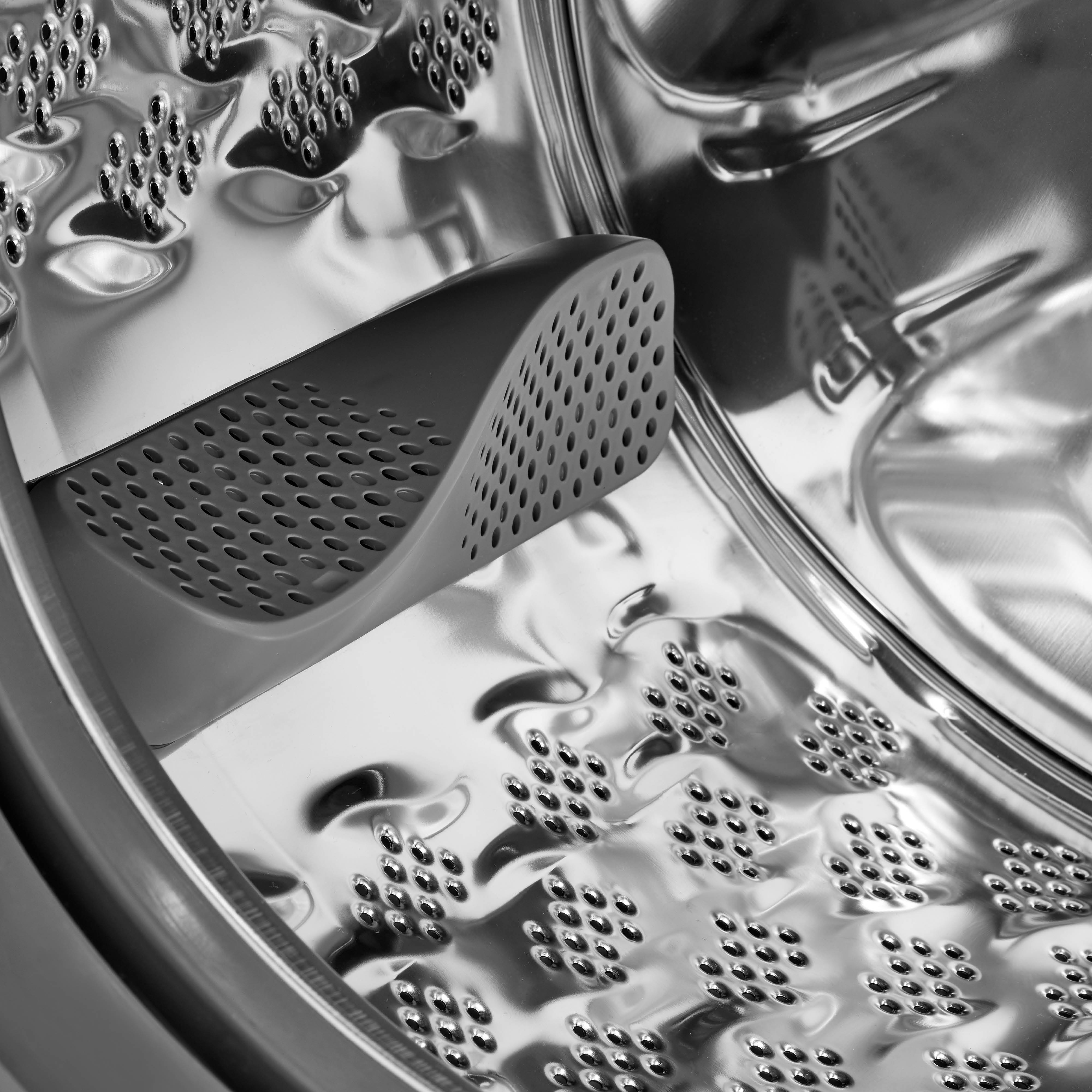 Close-up interieur van een wasmachinetrommel. Glanzend metalen oppervlak met gaten.