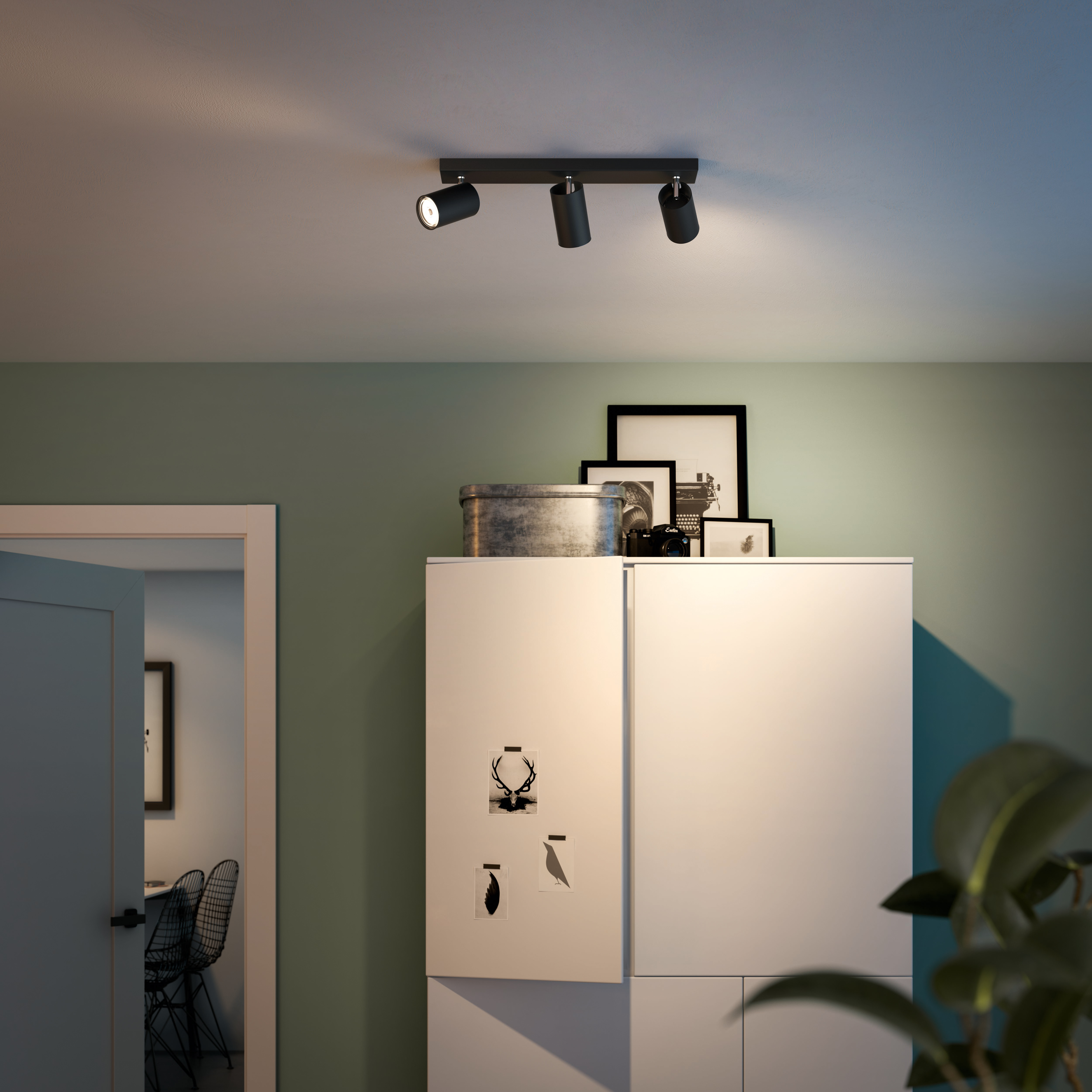 Drei schwarze Strahler auf einer schwarzen Stange, an der Decke montiert.