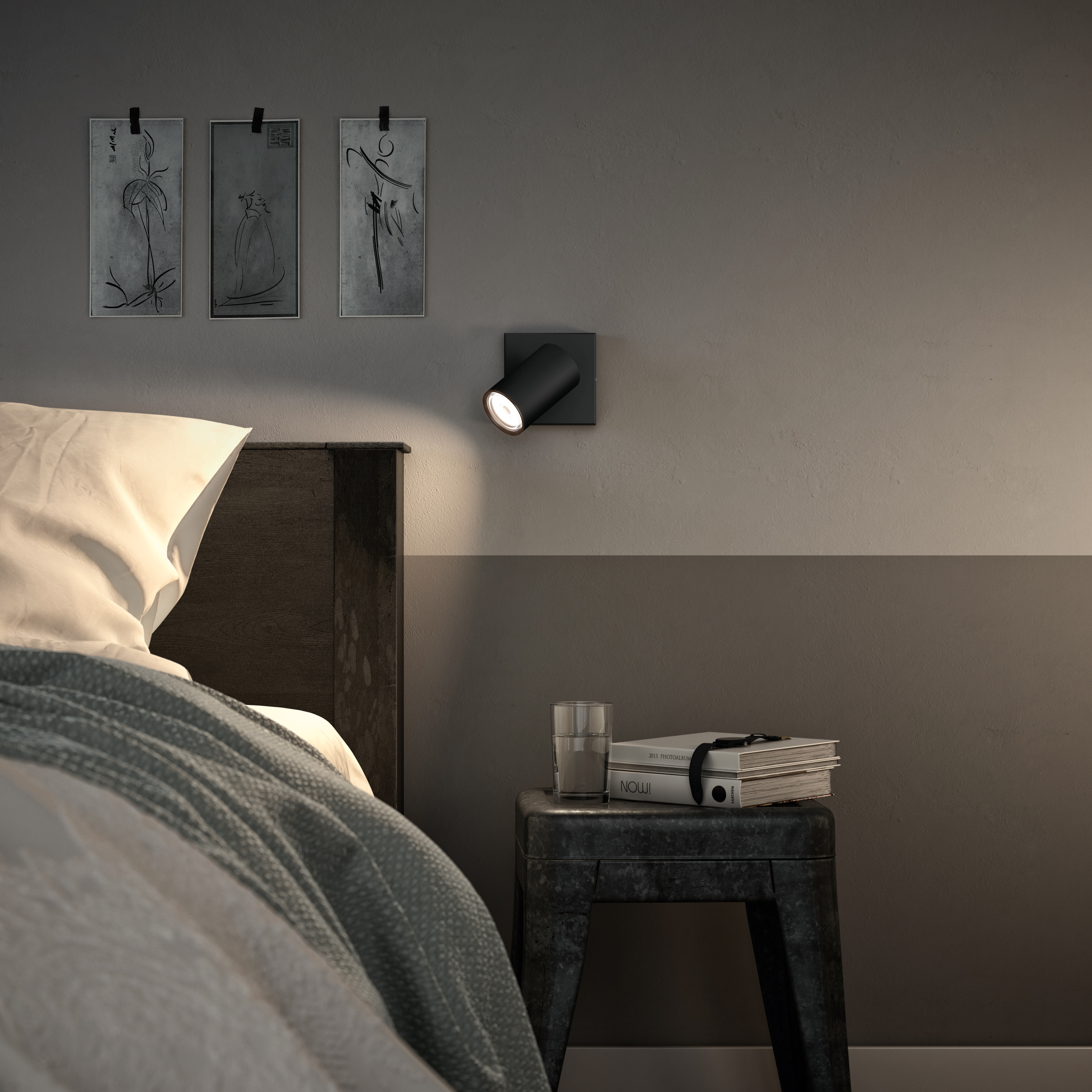 Ein Schlafzimmer mit einem schwarzen Wandstrahler und Kunstwerken an der Wand.