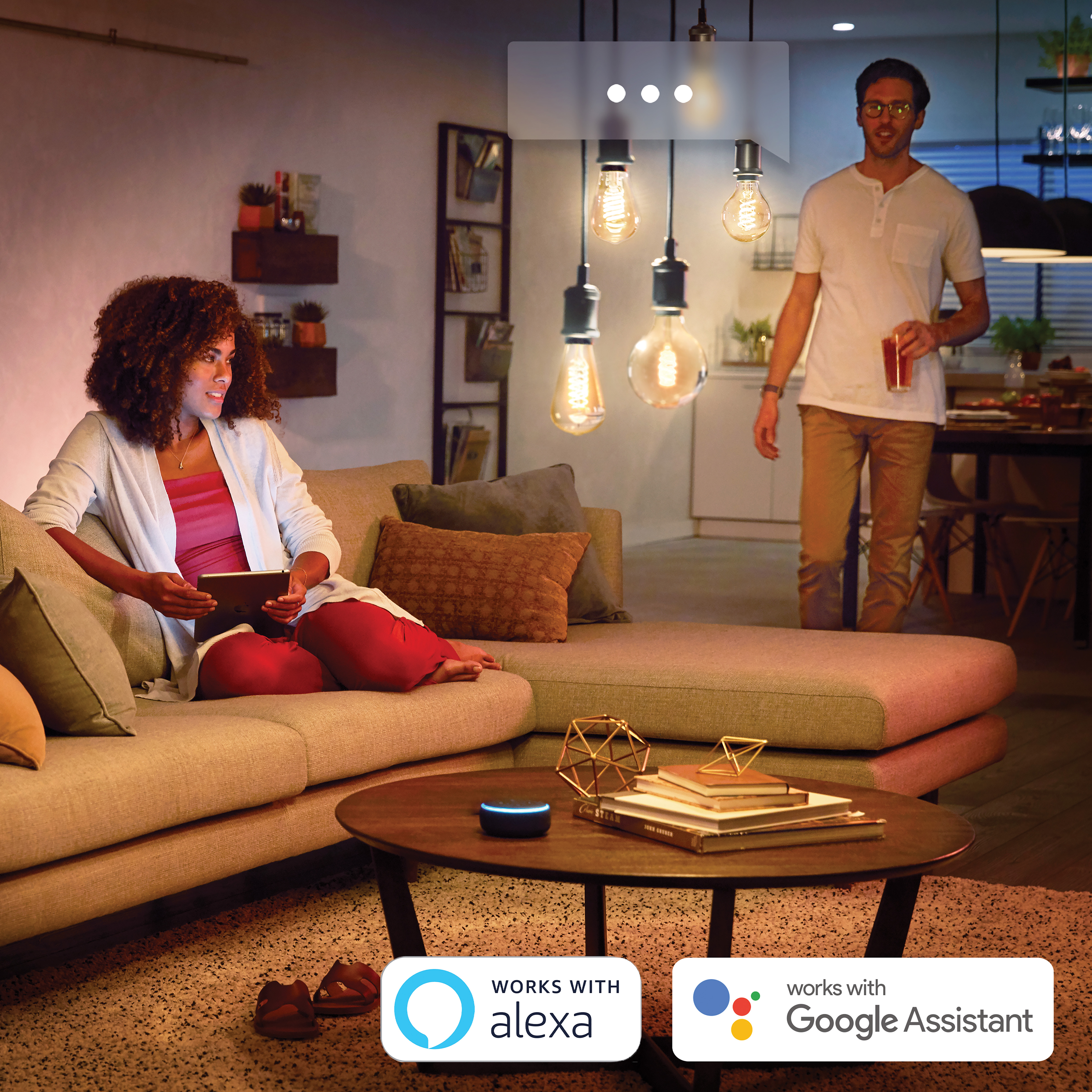 Leute in einem Wohnzimmer mit Hängelampen, Sofa, Couchtisch und Smart-Home-Geräten. Funktioniert mit Alexa & Google.