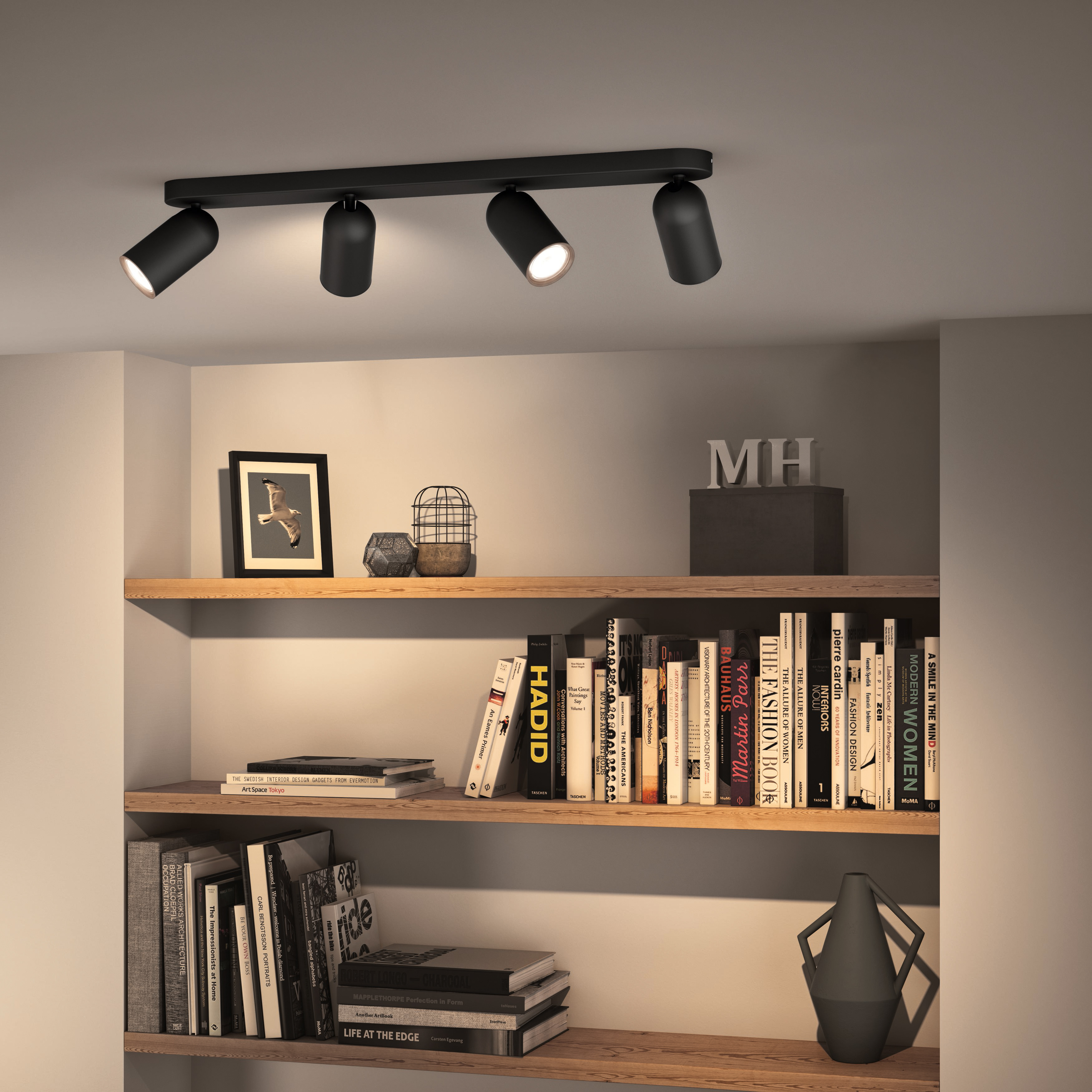 Schwarz Deckenstrahler mit vier verstellbaren Strahlern. Bücherregal im Hintergrund.