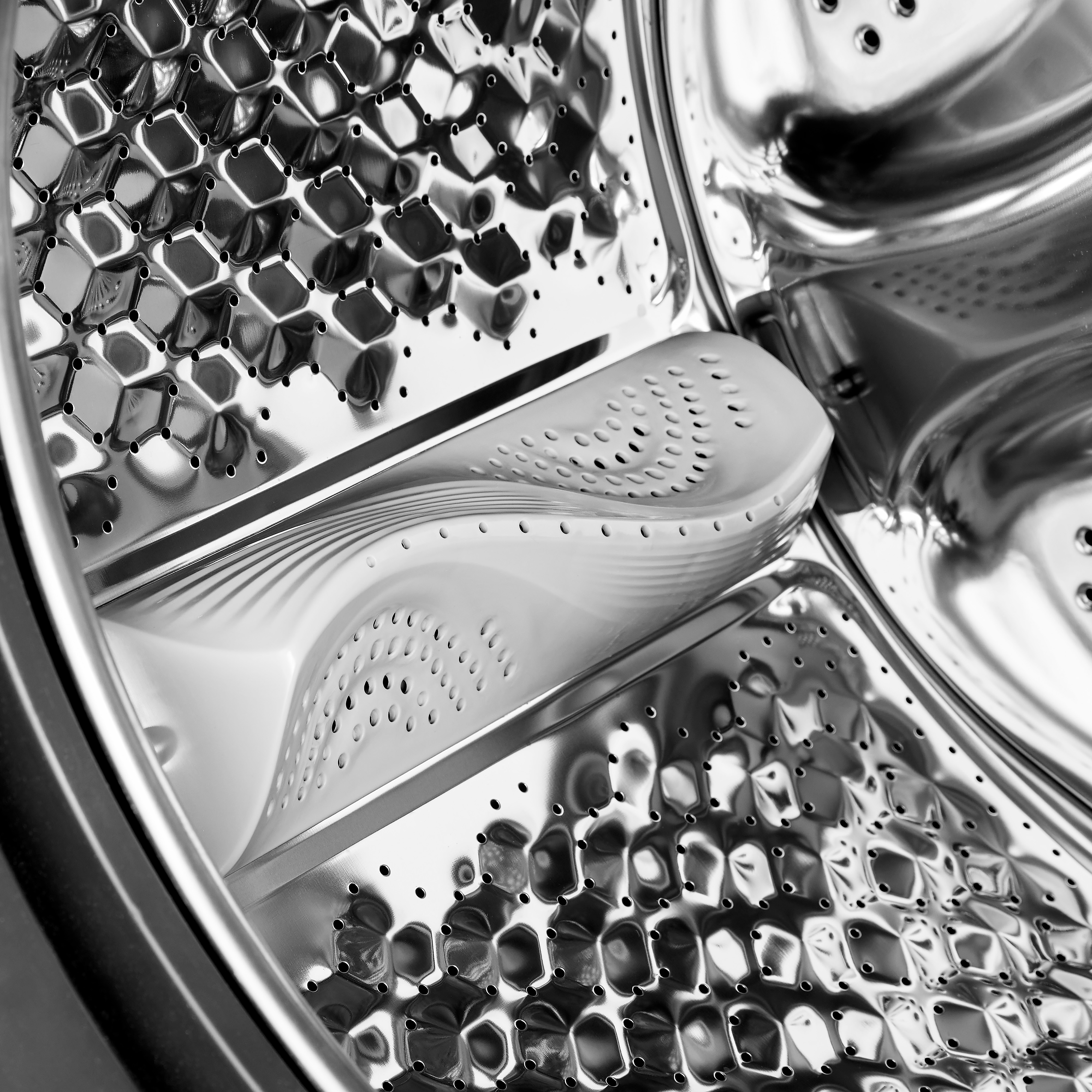 Close-up of a washing machine drum, showing metallic interior with holes and a white paddle.