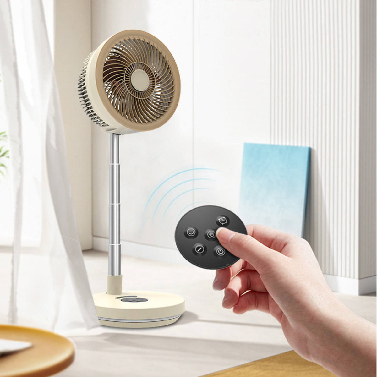 Beige und silberner Ventilator auf einem Ständer mit Fernbedienung in der Hand. Der Ventilator steht auf einer hellen Oberfläche.