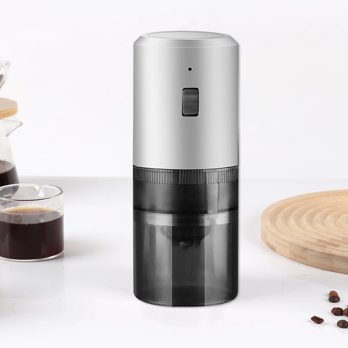 Eine silberne und schwarze Kaffeemühle. Sie hat einen Behälter für Bohnen, einen Knopf und einen Behälter für Kaffeepulver.