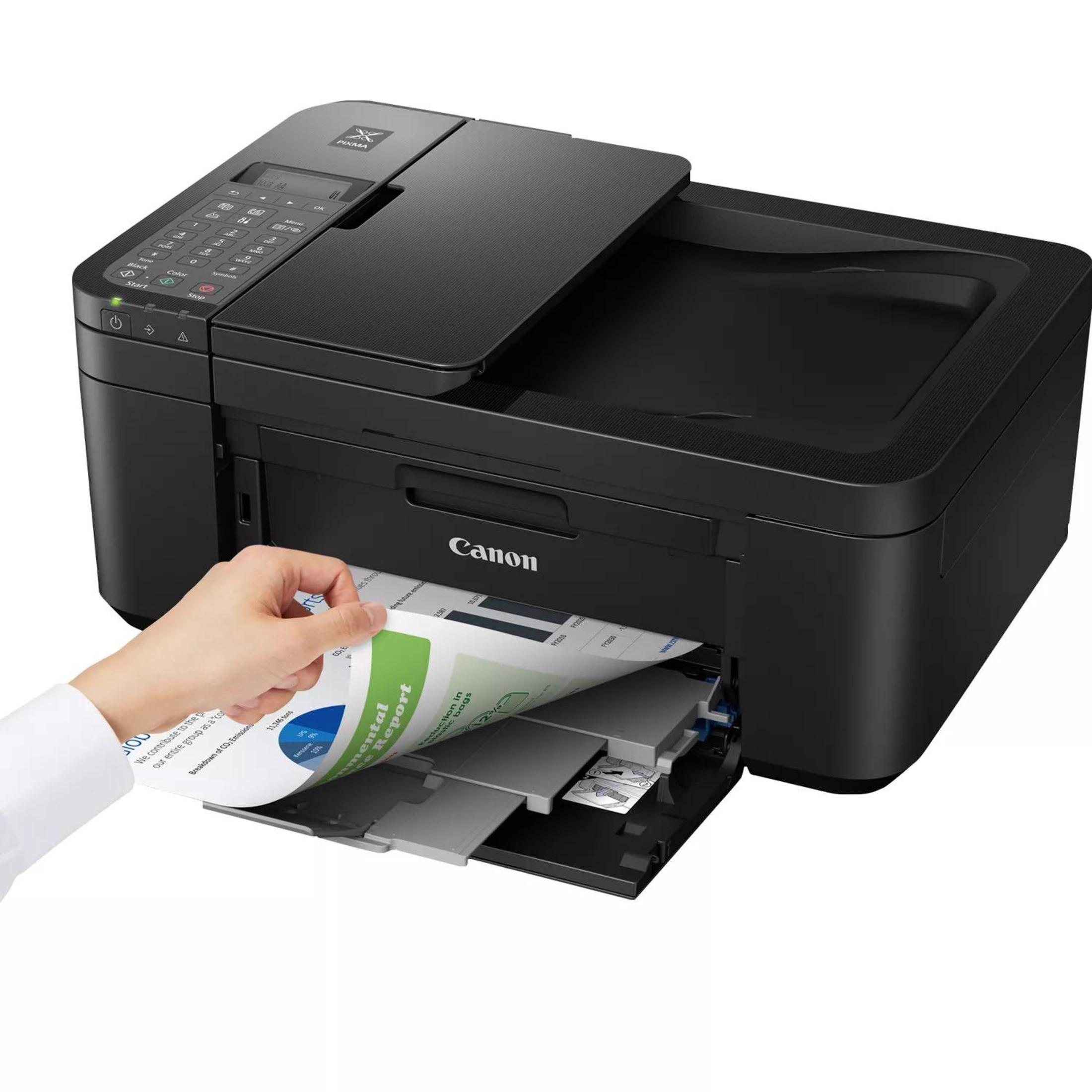 Stampante Canon nera, mano che inserisce una pagina da una pila di fogli.