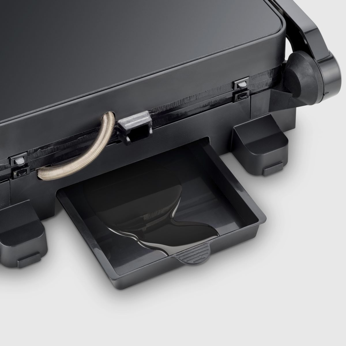 Close-up of a black appliance with a tray, showing dark liquid, likely oil.