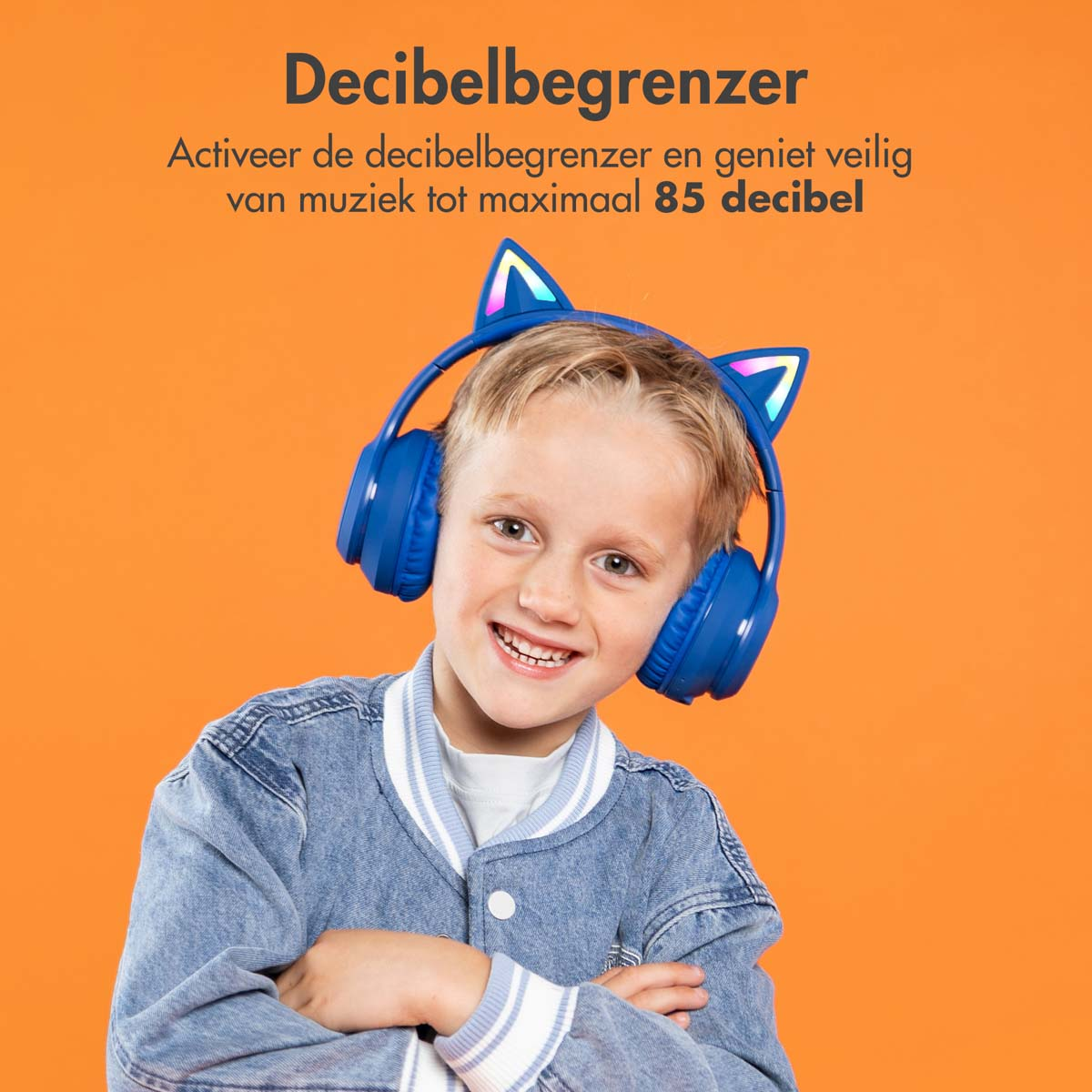 Jongen glimlacht, draagt blauwe kattenoorkoptelefoon en een spijkerjasje, oranje achtergrond.