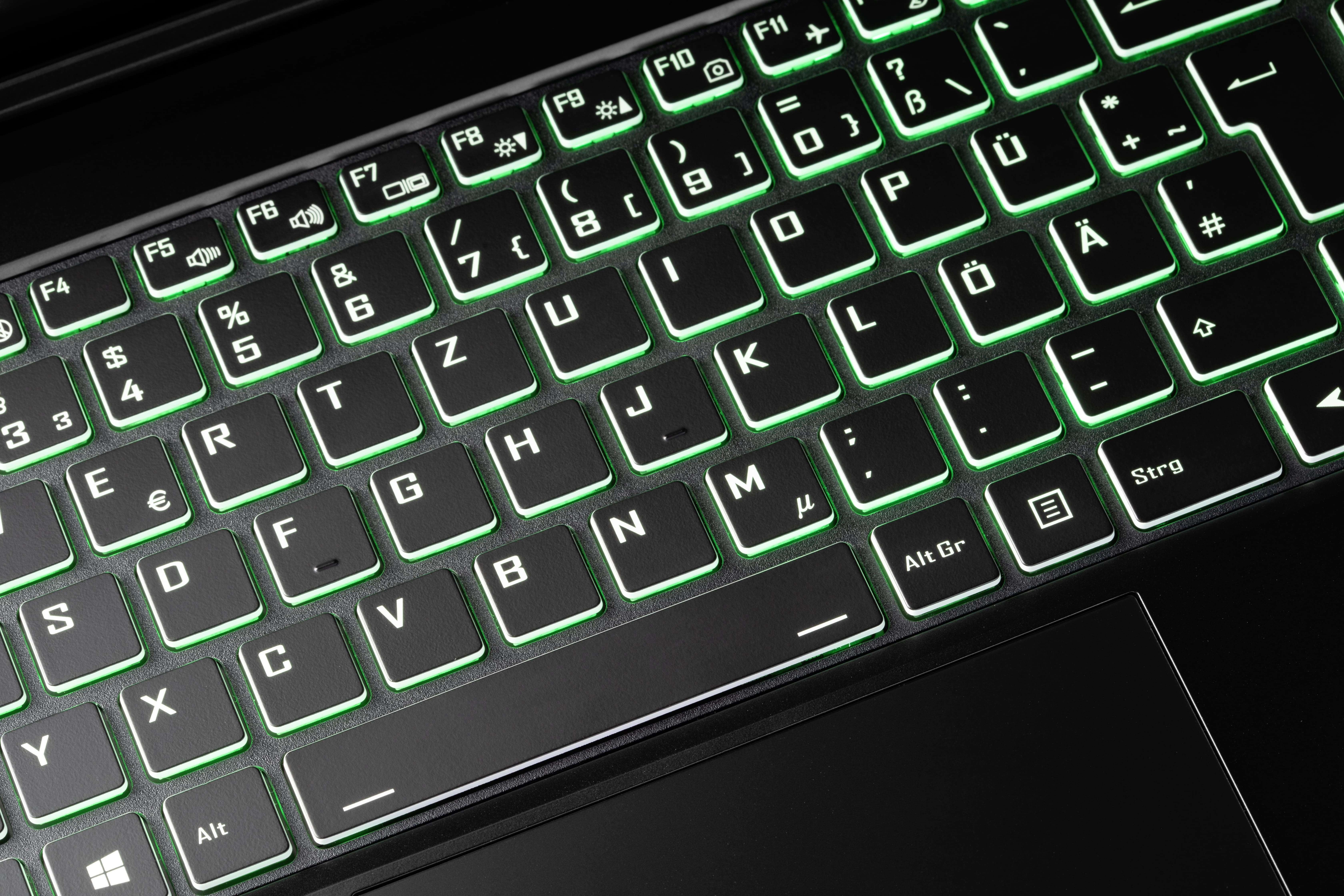 Nahaufnahme einer hintergrundbeleuchteten Tastatur. Grünes Licht. Schwarze Tasten und Rahmen. Buchstaben sichtbar.