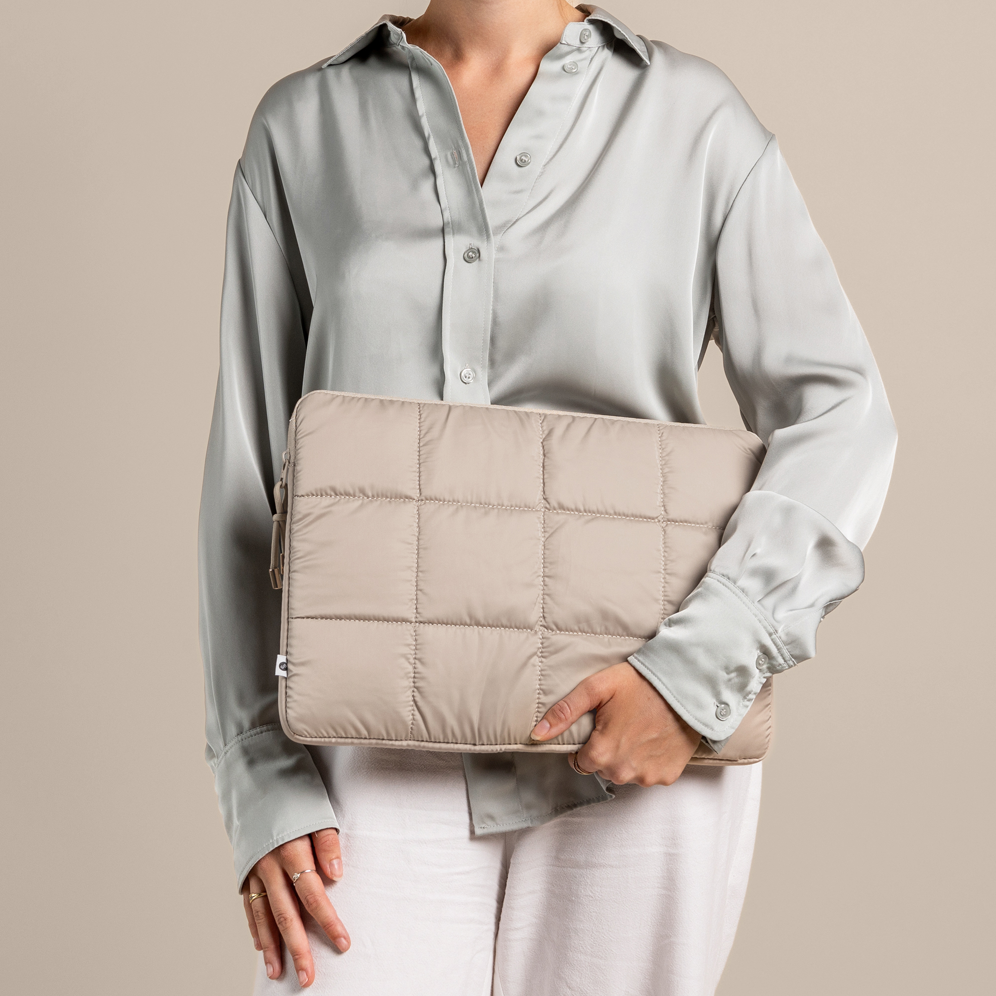 A woman holding a beige laptop case, with a light green shirt.