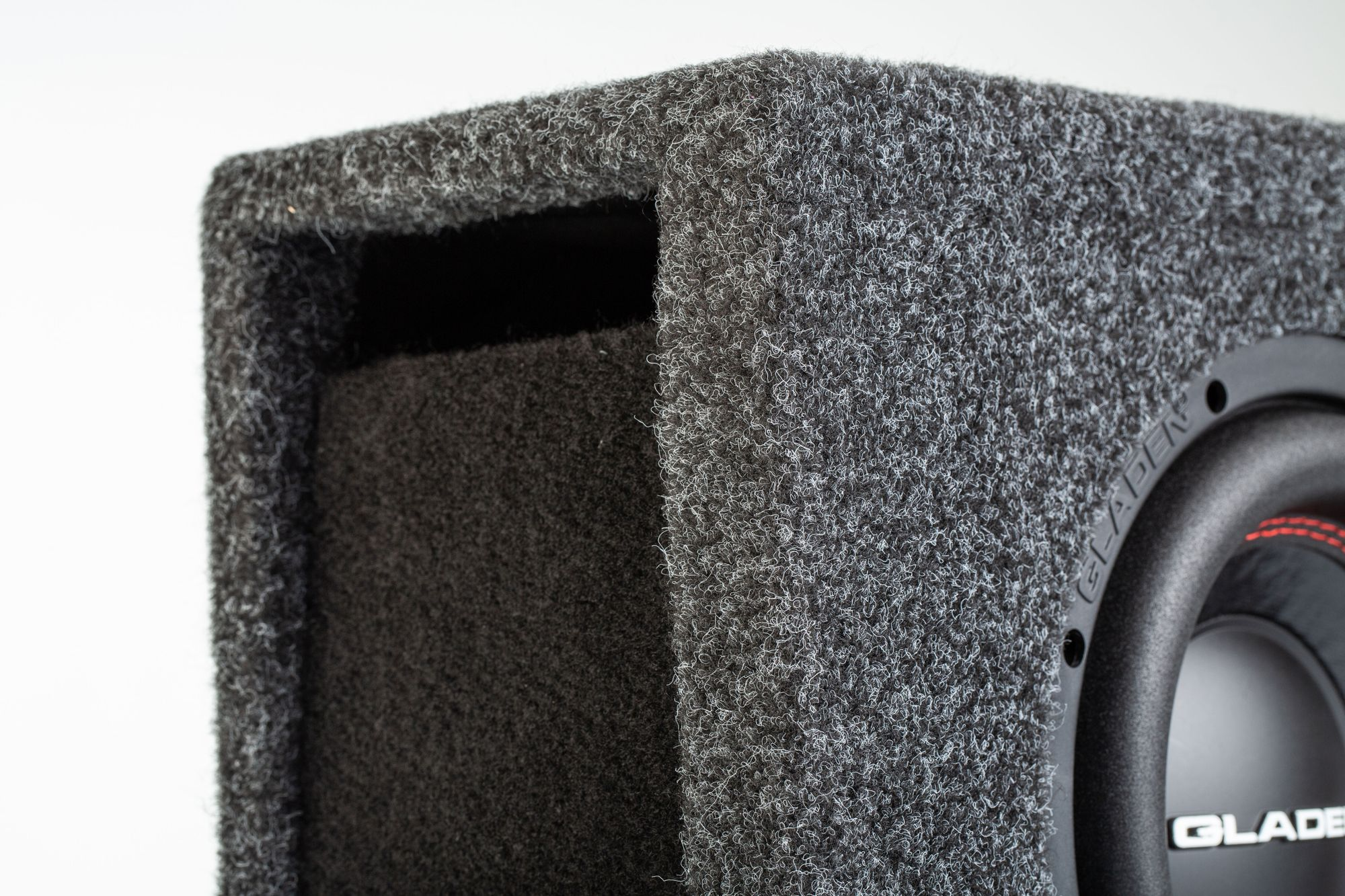 Nahaufnahme einer grauen Subwoofer-Box. Sie hat einen Lautsprecher, einen Anschluss und eine strukturierte Oberfläche.