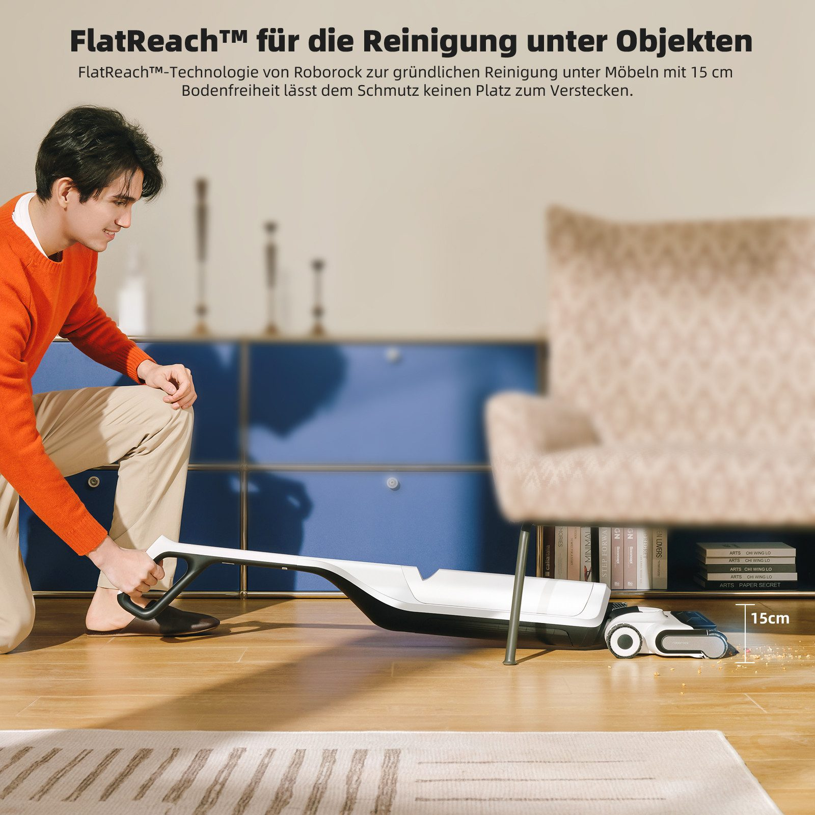 Mann benutzt Staubsauger unter Möbeln. Text sagt 'FlatReach™' und '15cm'.