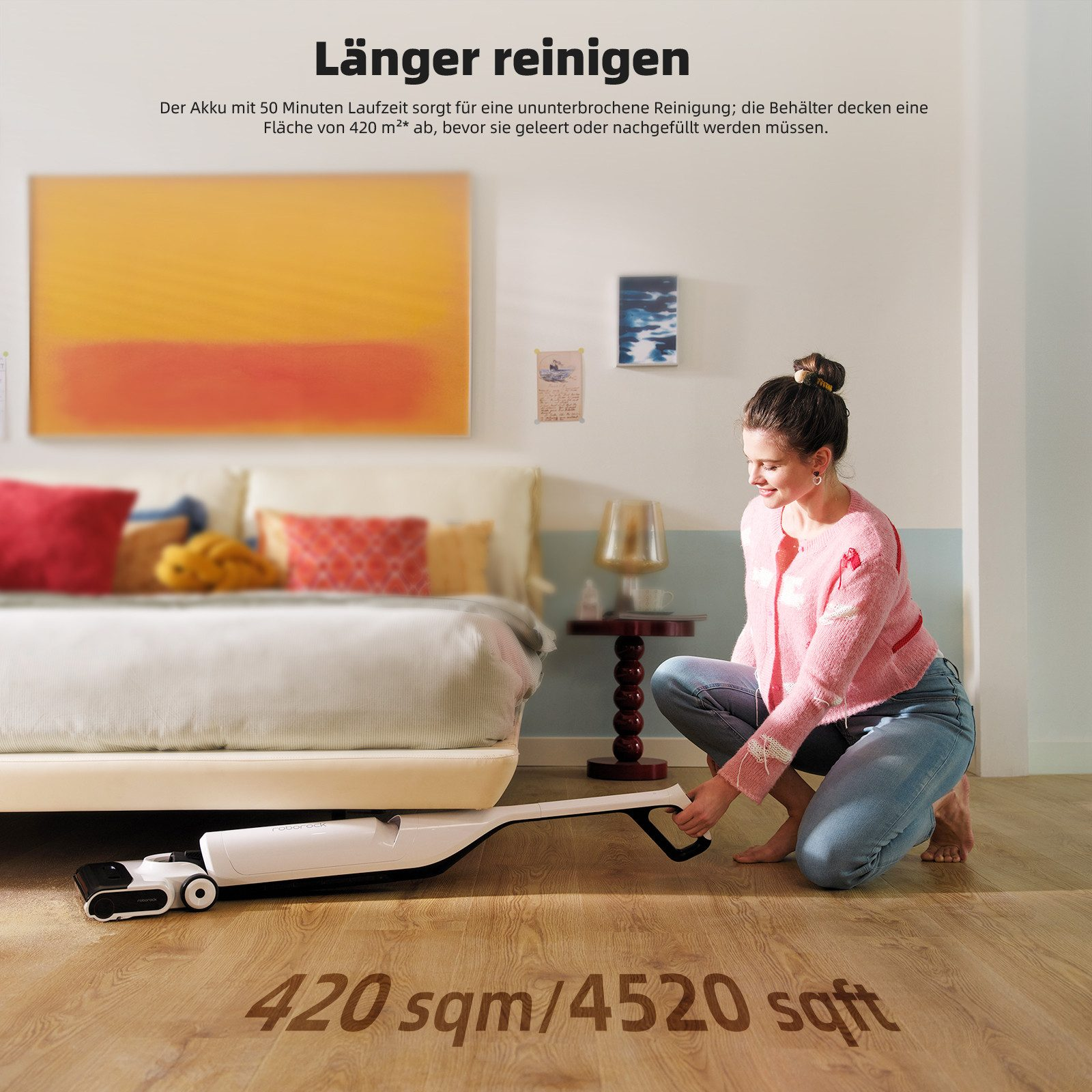 Frau reinigt den Boden mit einem weißen Staubsauger. Gelbes und oranges abstraktes Gemälde an der Wand.