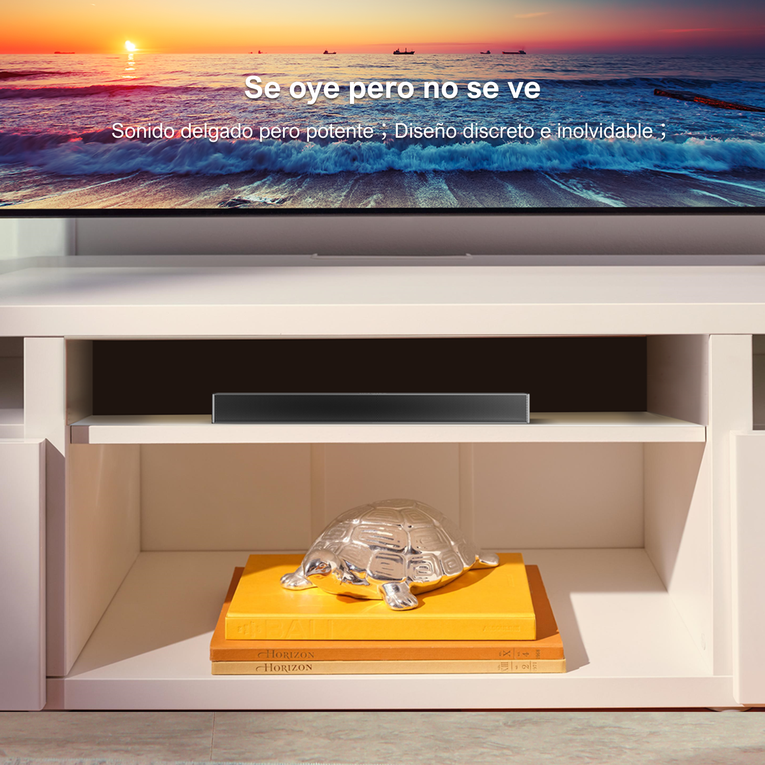 TV en un mueble blanco con barra de sonido, tortuga plateada en libros. Puesta de sol al fondo.