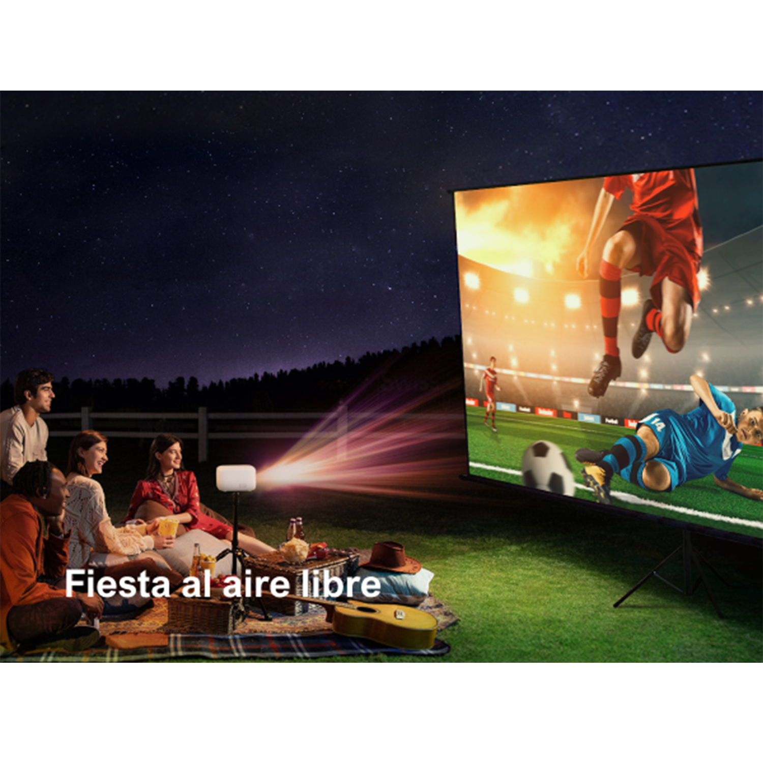Grupo de personas en picnic nocturno, viendo partido de fútbol proyectado en pantalla. Estrellas visibles.