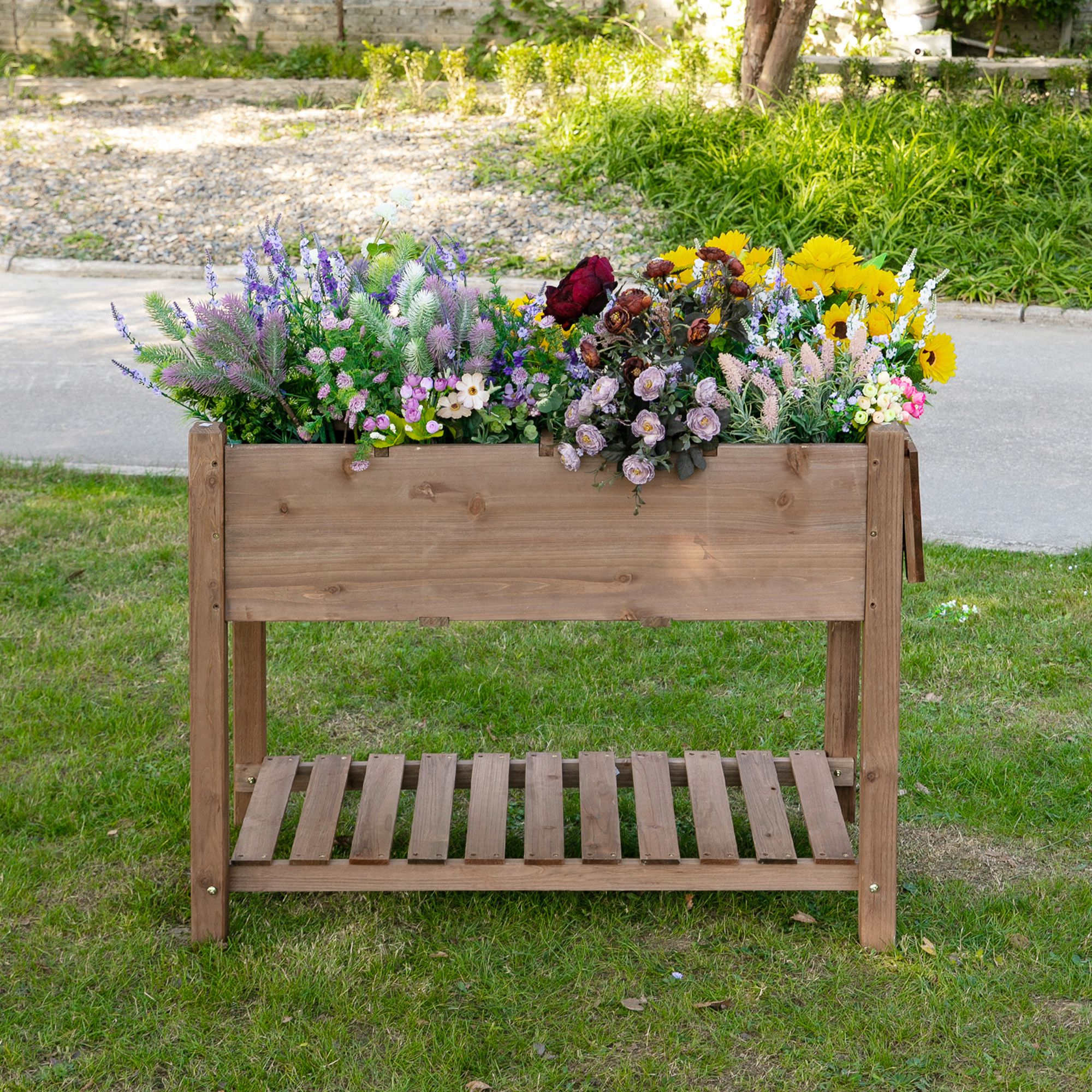 Un'aiuola rialzata in legno piena di una varietà di fiori colorati su un prato verde.