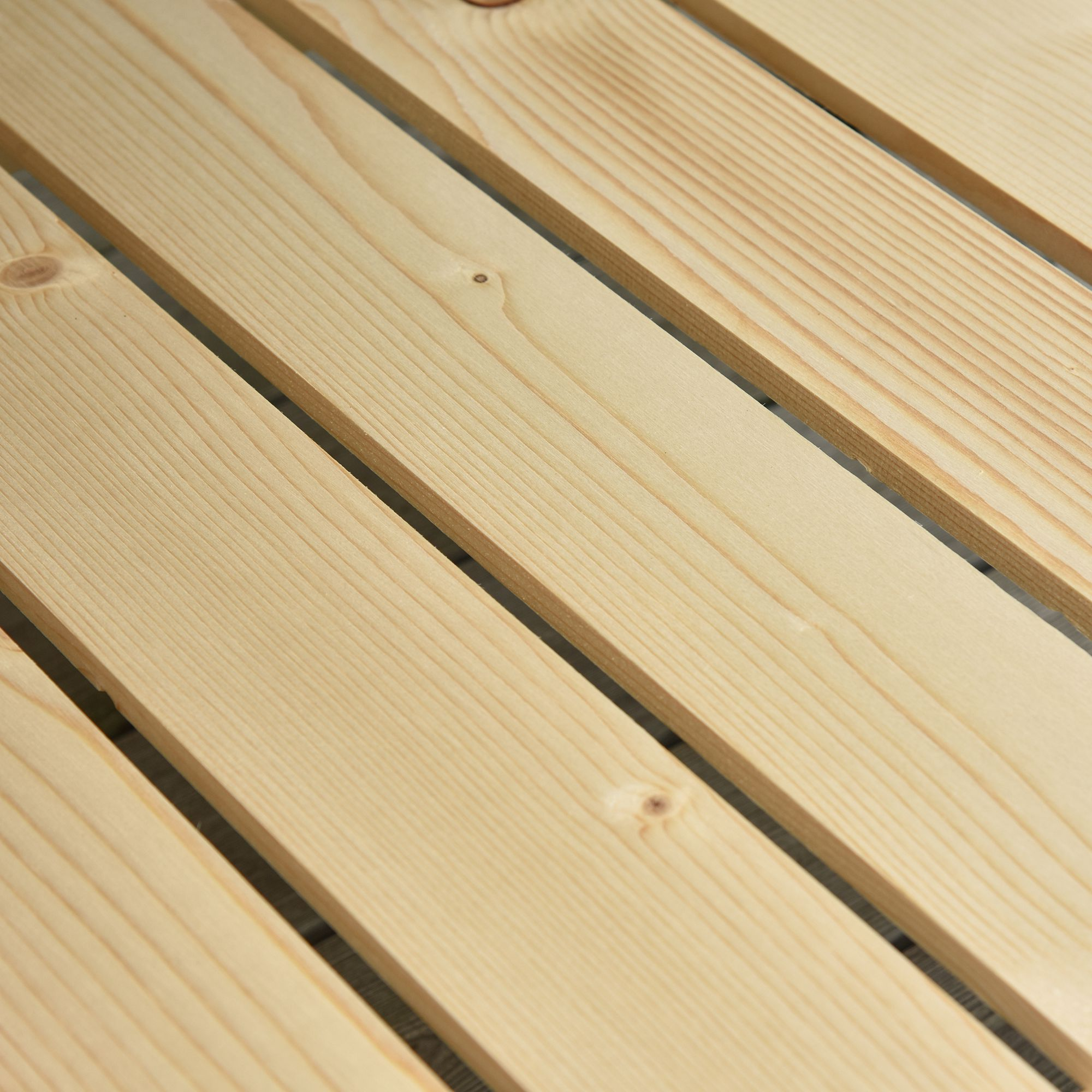 Primo piano di assi di legno. Le assi sono marrone chiaro, disposte parallelamente. La venatura del legno è visibile.