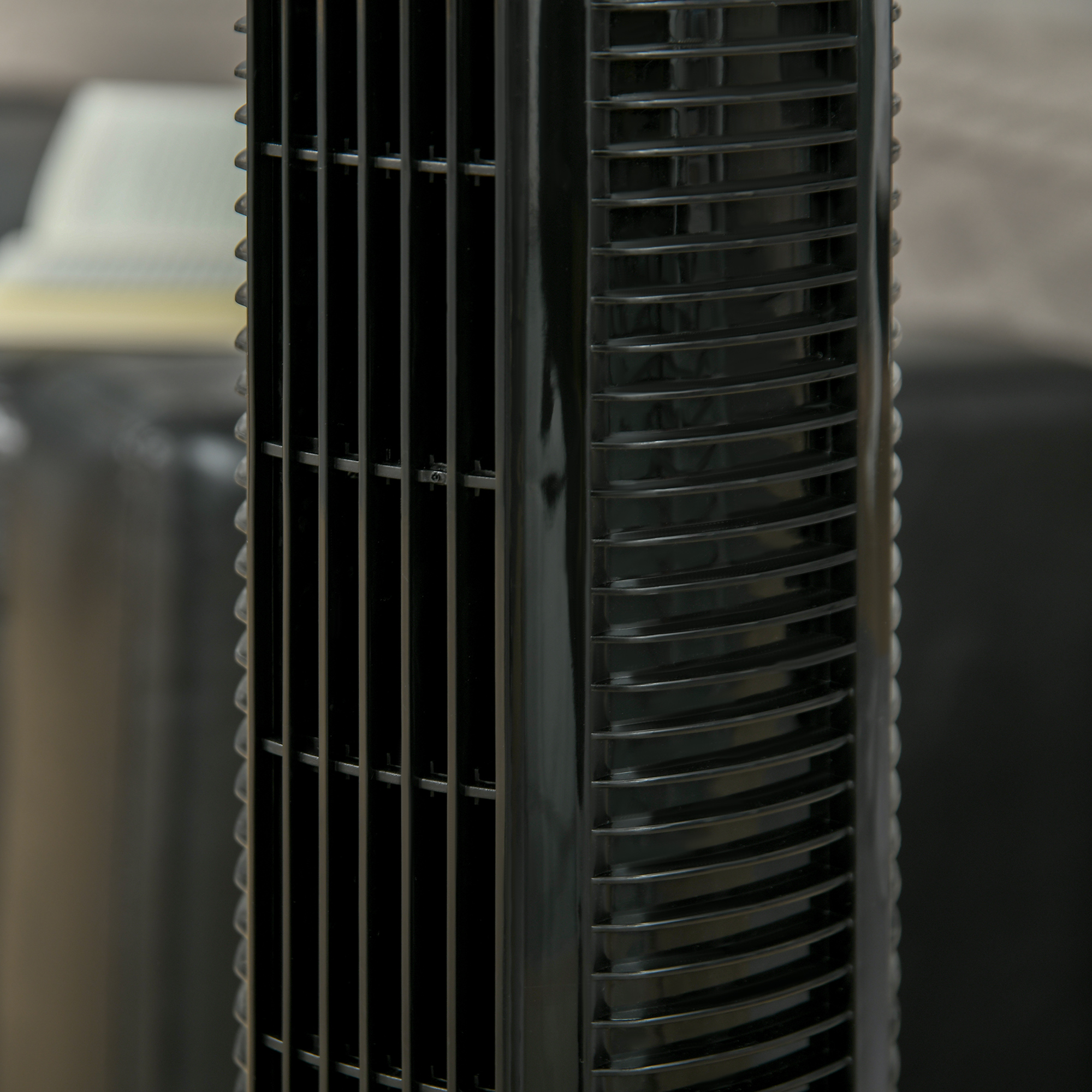 Primo piano della parte anteriore di un ventilatore a torre nero. Barre nere verticali coprono l'interno.