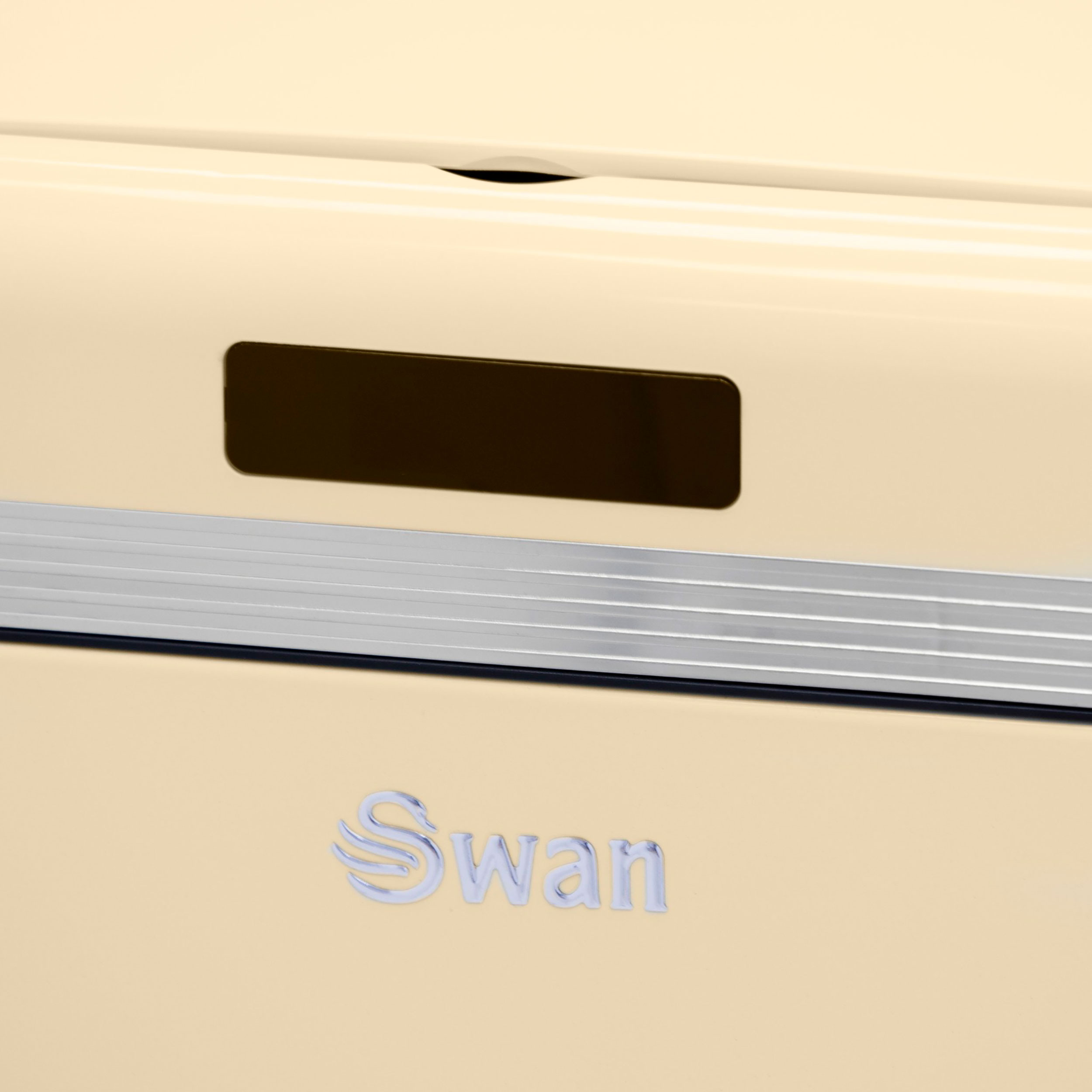 Primer plano de electrodoméstico beige con asa, franja plateada y logo Swan.