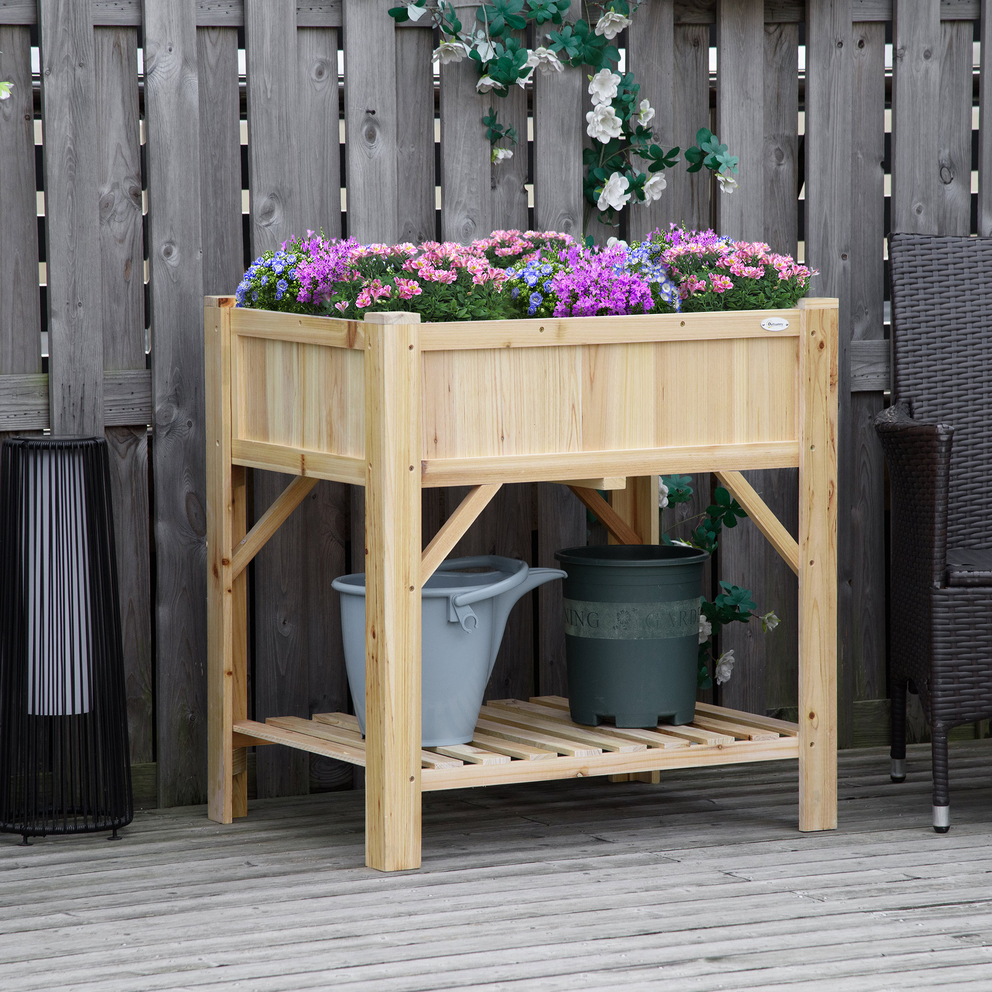 Fioriera in legno su gambe, piena di fiori colorati. Secchio grigio e vaso verde sul ripiano inferiore.