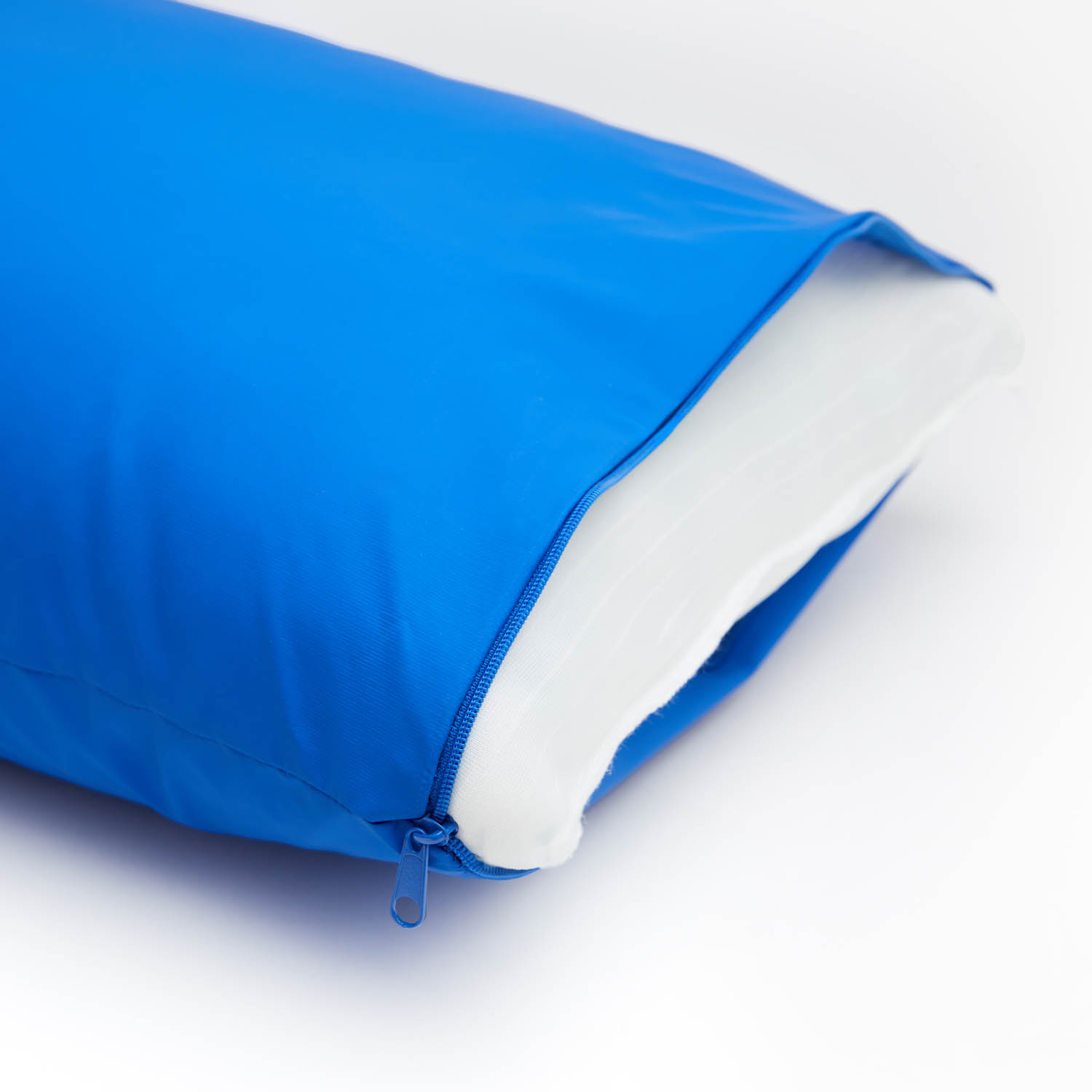 Funda de almohada azul con cremallera abierta, revelando almohada blanca. Fondo blanco. Primer plano.