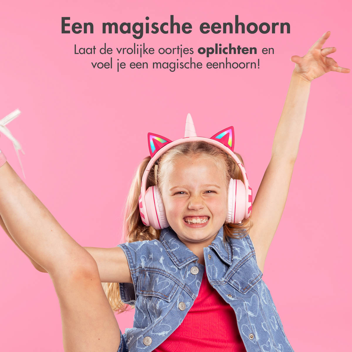 Una ragazza indossa delle cuffie a unicorno rosa e sorride con le braccia alzate.