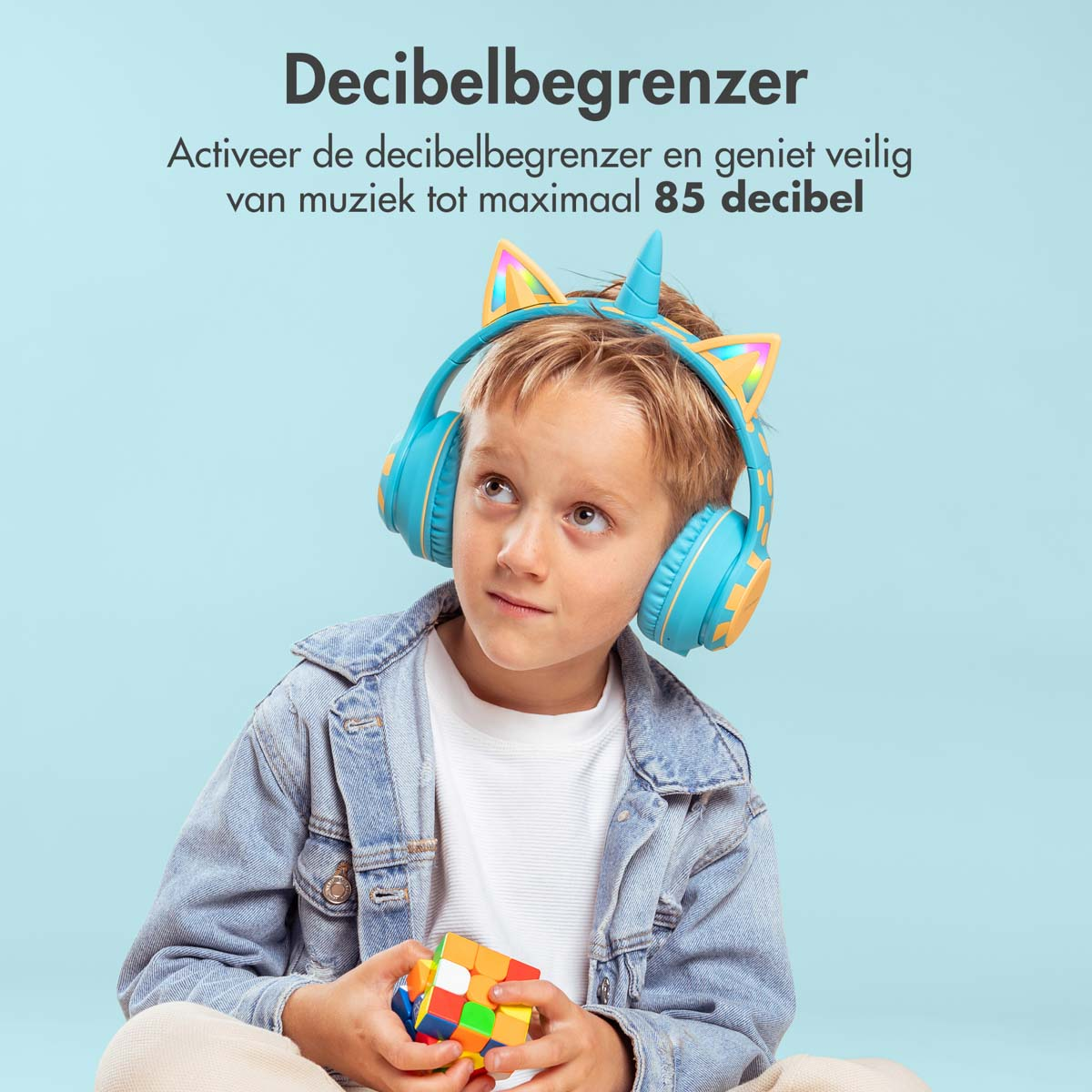 Een jongen met blauwe en gele eenhoorn koptelefoon, Rubik's Cube, lichtblauwe achtergrond.
