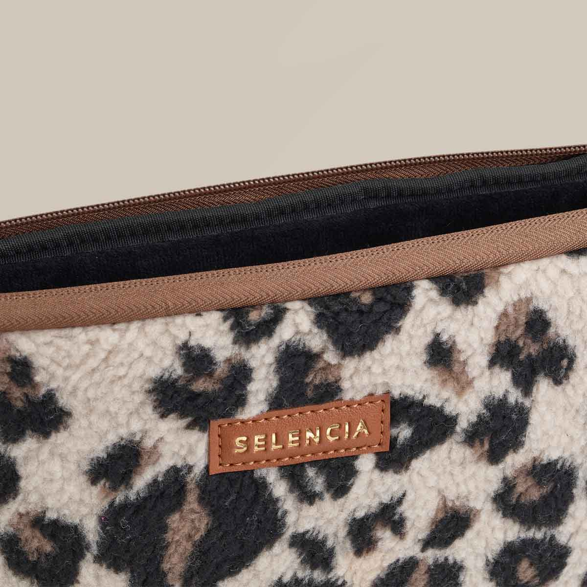 Primer plano de una funda para portátil con estampado de leopardo. La etiqueta de cuero marrón dice SELENCIA.