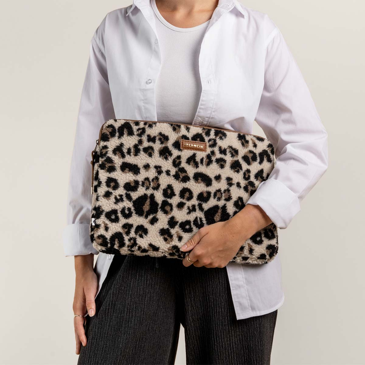 Una persona sosteniendo una funda para portátil con estampado de leopardo.